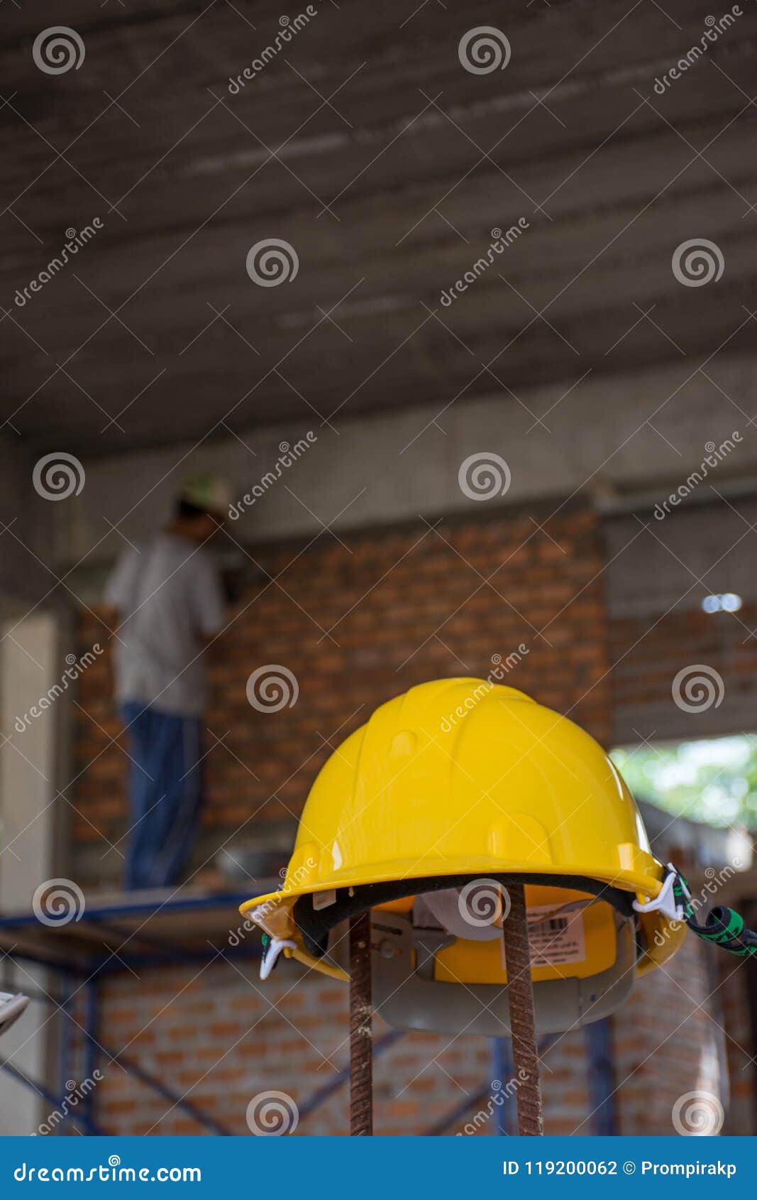 Capacete de segurança amarelo com o trabalhador da construção que coloca tijolos sobre. Capacete de segurança amarelo com o trabalhador da construção que coloca tijolos no cimento para construir paredes exteriores