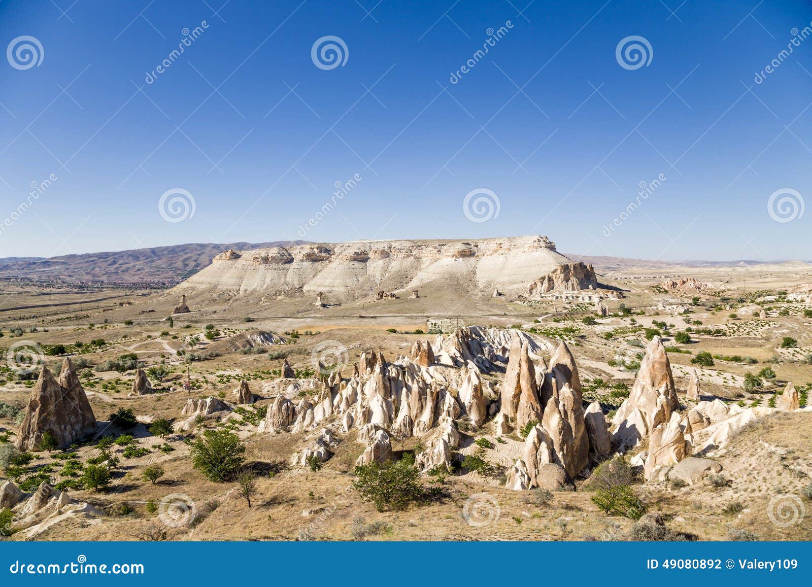 Cappadocia, Turquía Paisaje de la montaña cerca de Cavusin con los pilares de la erosión (afloramientos de roca). Cappadocia - el nombre histórico del área en el este Asia Menor en Turquía moderna (parte de las provincias de la tierra de Nevsehir, de Kayseri, de Aksaray y de Nigde) se utiliza desde antigüedad al hoy Caracterizado por un paisaje extremadamente interesante del origen volcánico, de las ciudades subterráneos, creados en 1r mil A.C. y los monasterios extensos de la cueva, llevando su historia desde los días de los cristianos tempranos Los acuerdos de la cueva del parque nacional y de Cappadocia de GÃ¶reme se incluyen en sitio del patrimonio mundial de la UNESCO Una de las áreas más interesantes de Cappadocia es el área del ‹del â€ del ‹del â€ el pueblo de Cavusin, cerca del cual hay un gran número de viviendas de cueva en las iglesias y los monasterios de la roca ANUNCIO de 5 - 10 siglos y las formaciones de roca hermosas