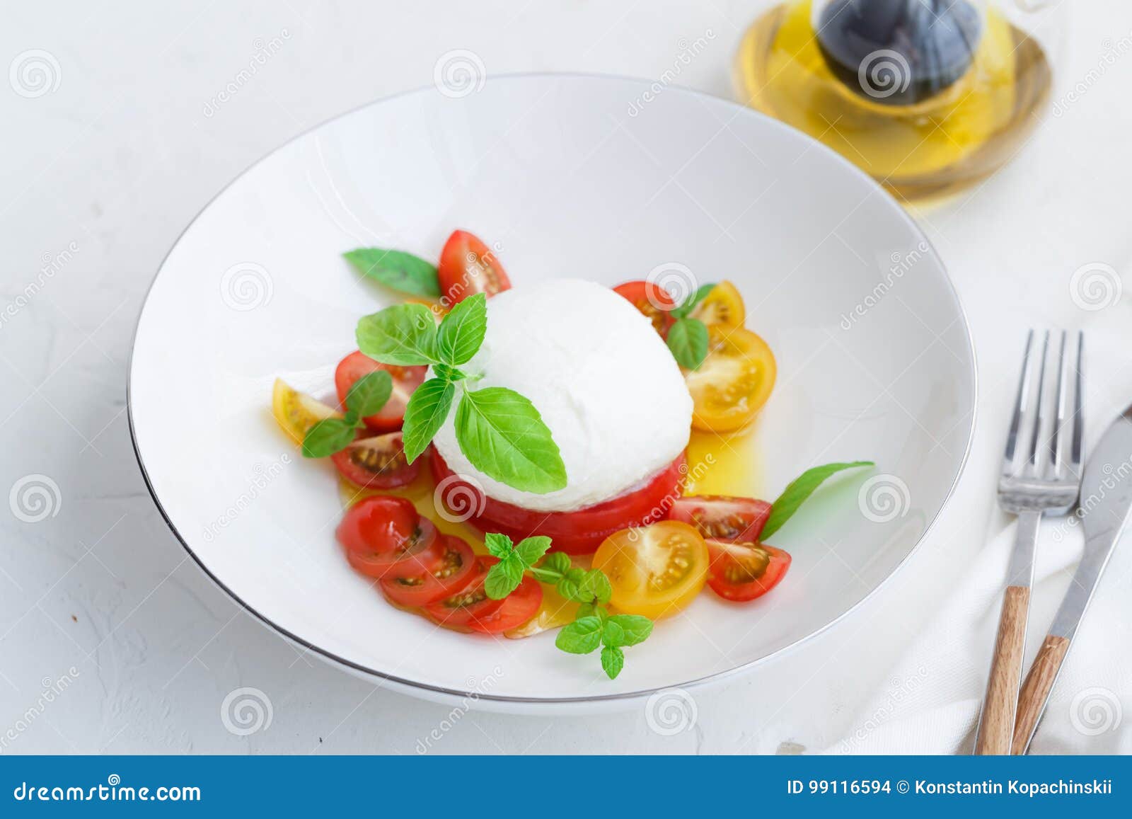 caprese salad with red and yellow tomatoes, mozarella, basil and olive oil. close view. white background