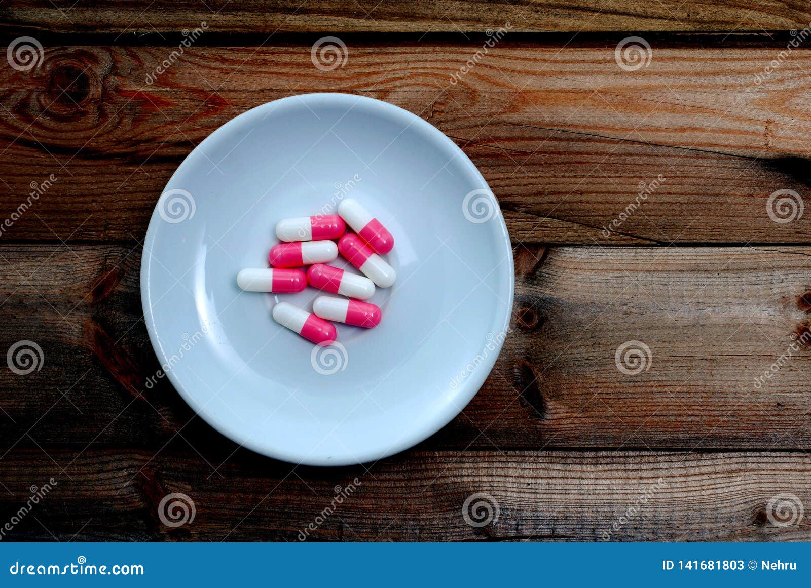 capsules in white plate on wood background