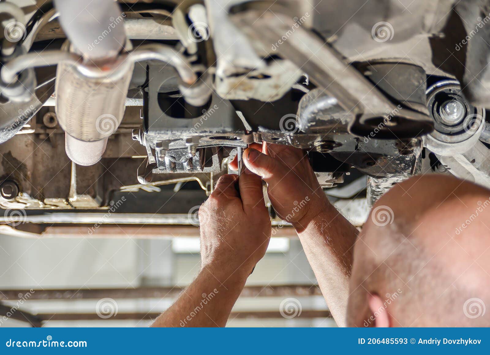 A Car Mechanic Repairs the Chassis of a Car Standing on a Lift Stock