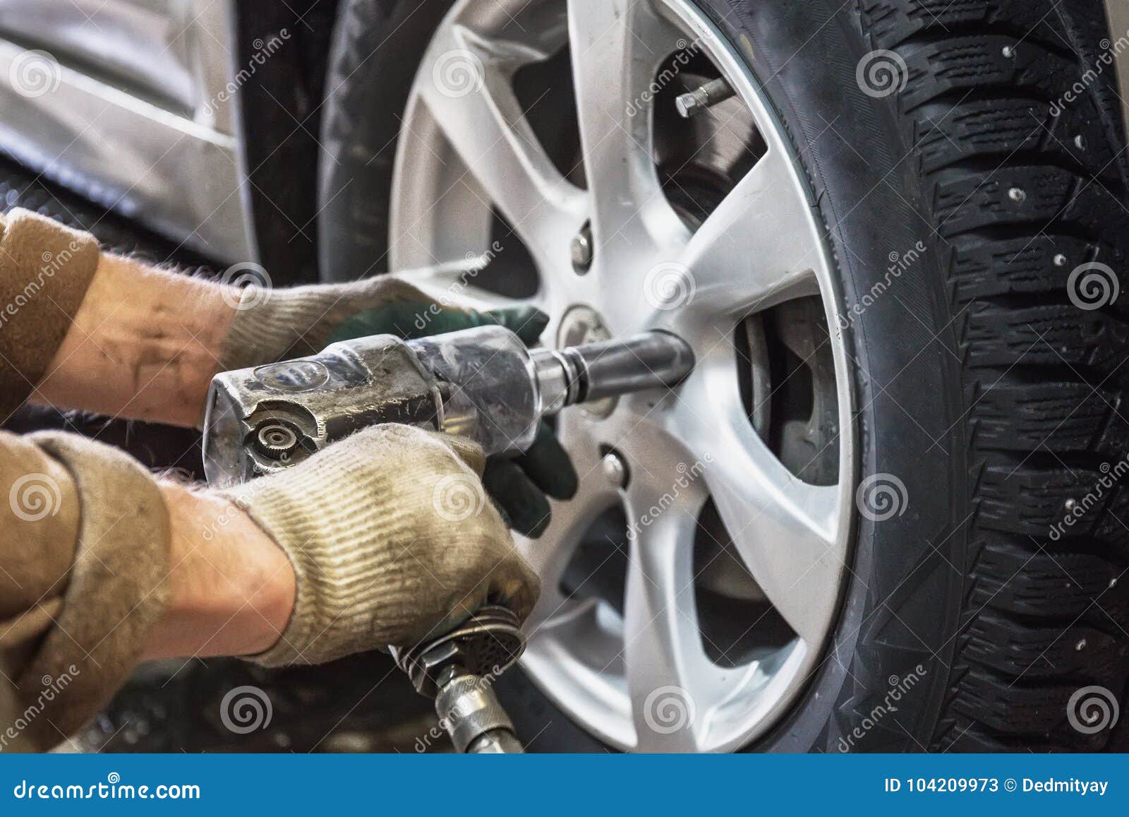 car mechanic replace car wheels of lifted automobile by pneumatic wrench at repair service shop garage station