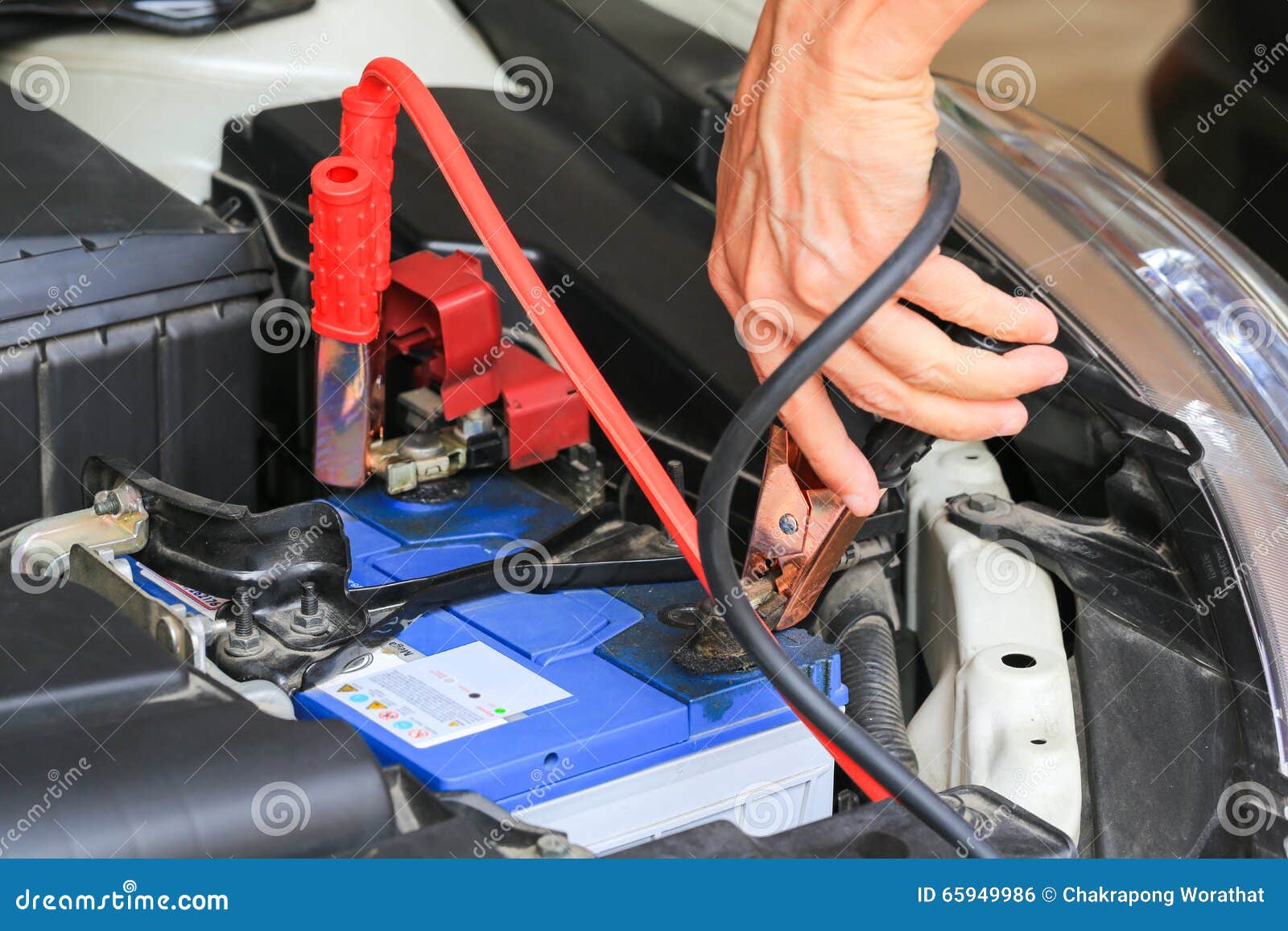 car mechanic uses battery jumper cables charge a dead battery.