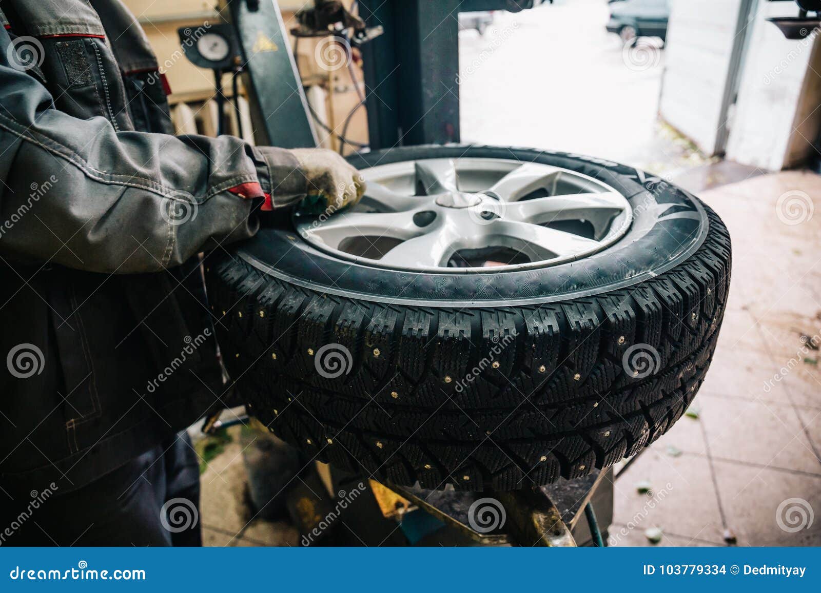 car mechanic worker doing tire replacement and wheel balancing with special equipment in repair service station