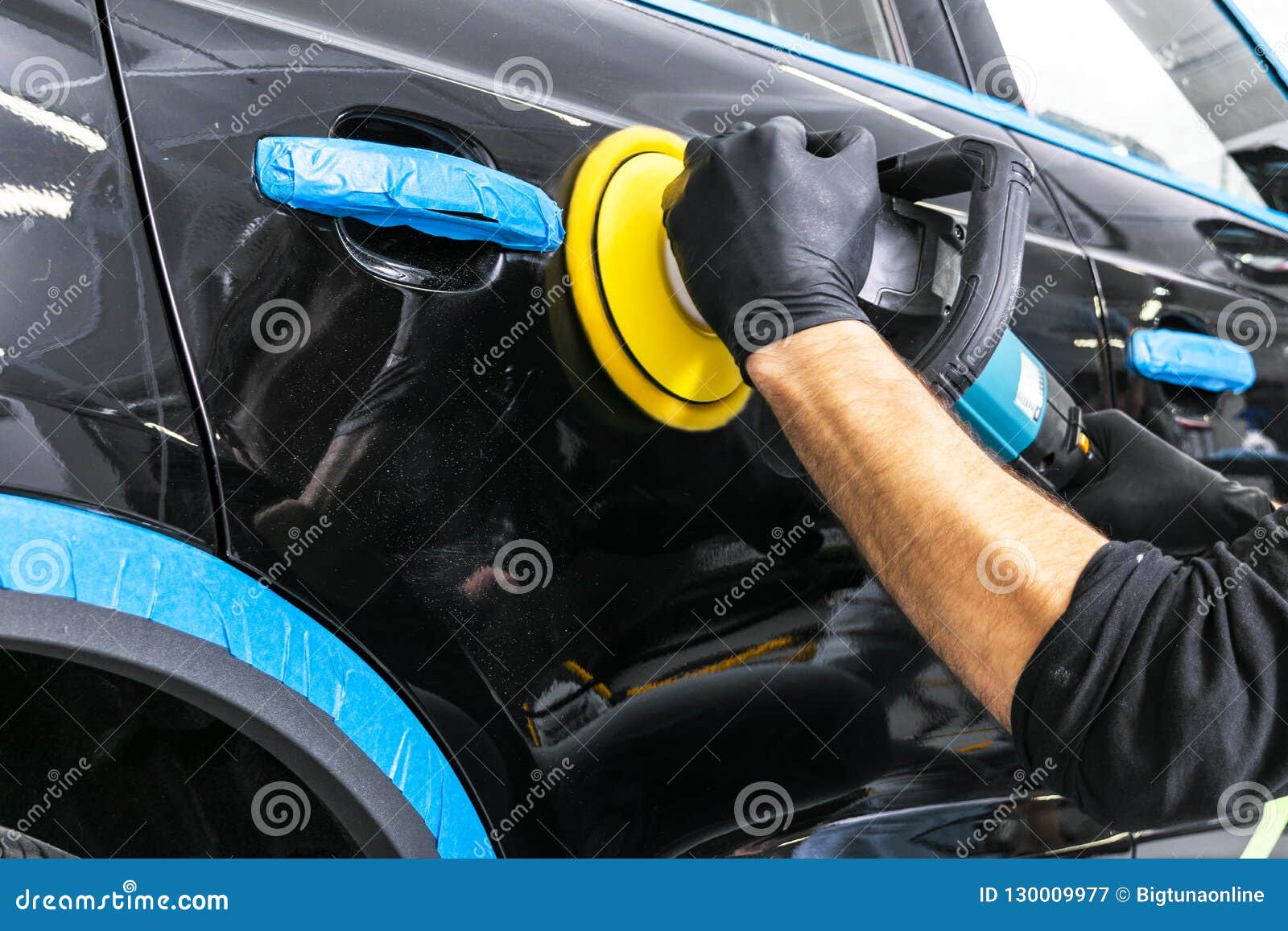 car polish wax worker hands applying protective tape before polishing. buffing and polishing car. car detailing. man holds a polis