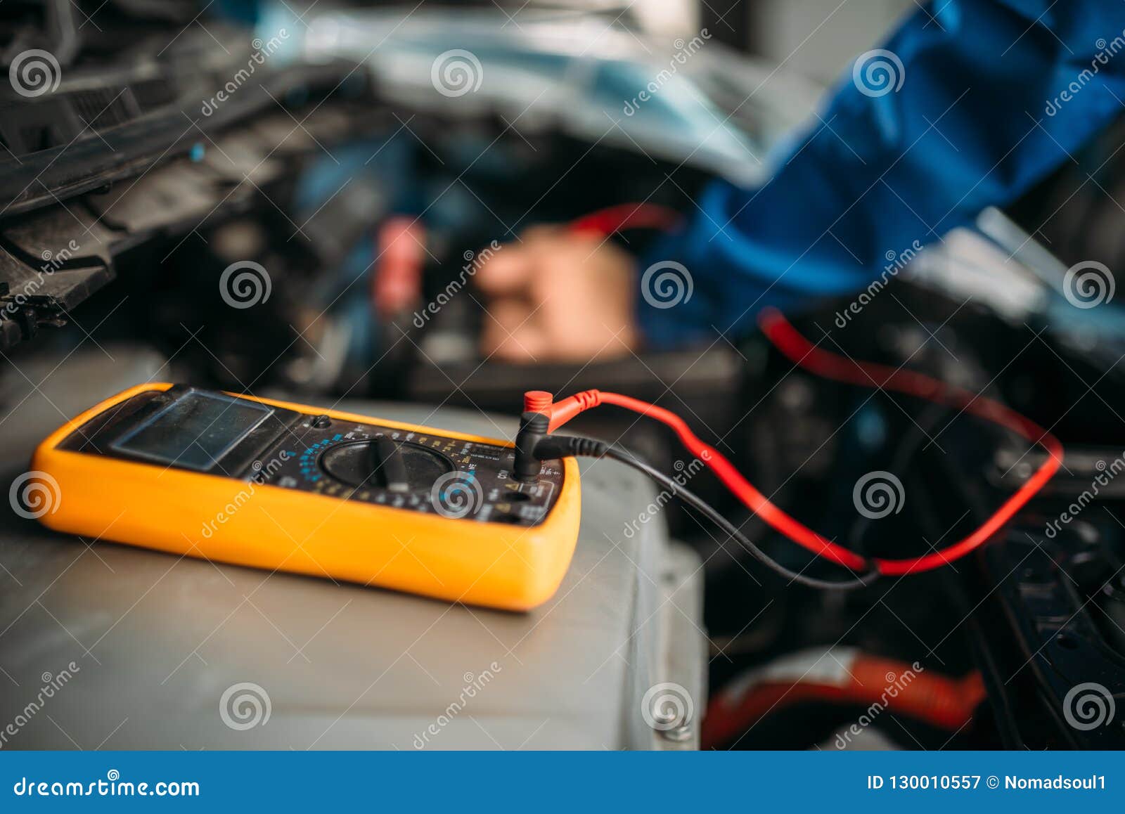 car repairman with multimeter, battery inspection