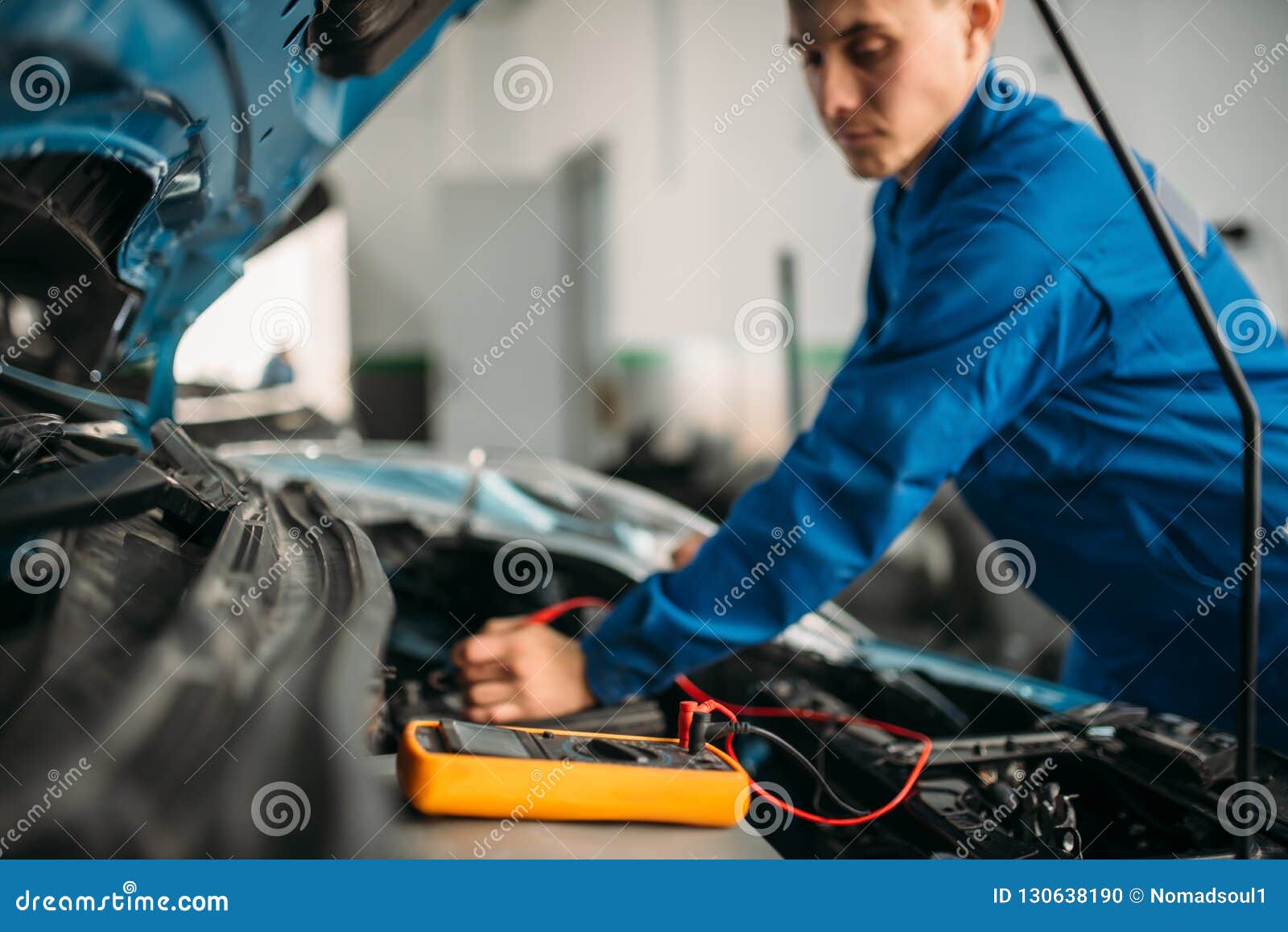 car repairman with multimeter, battery inspection
