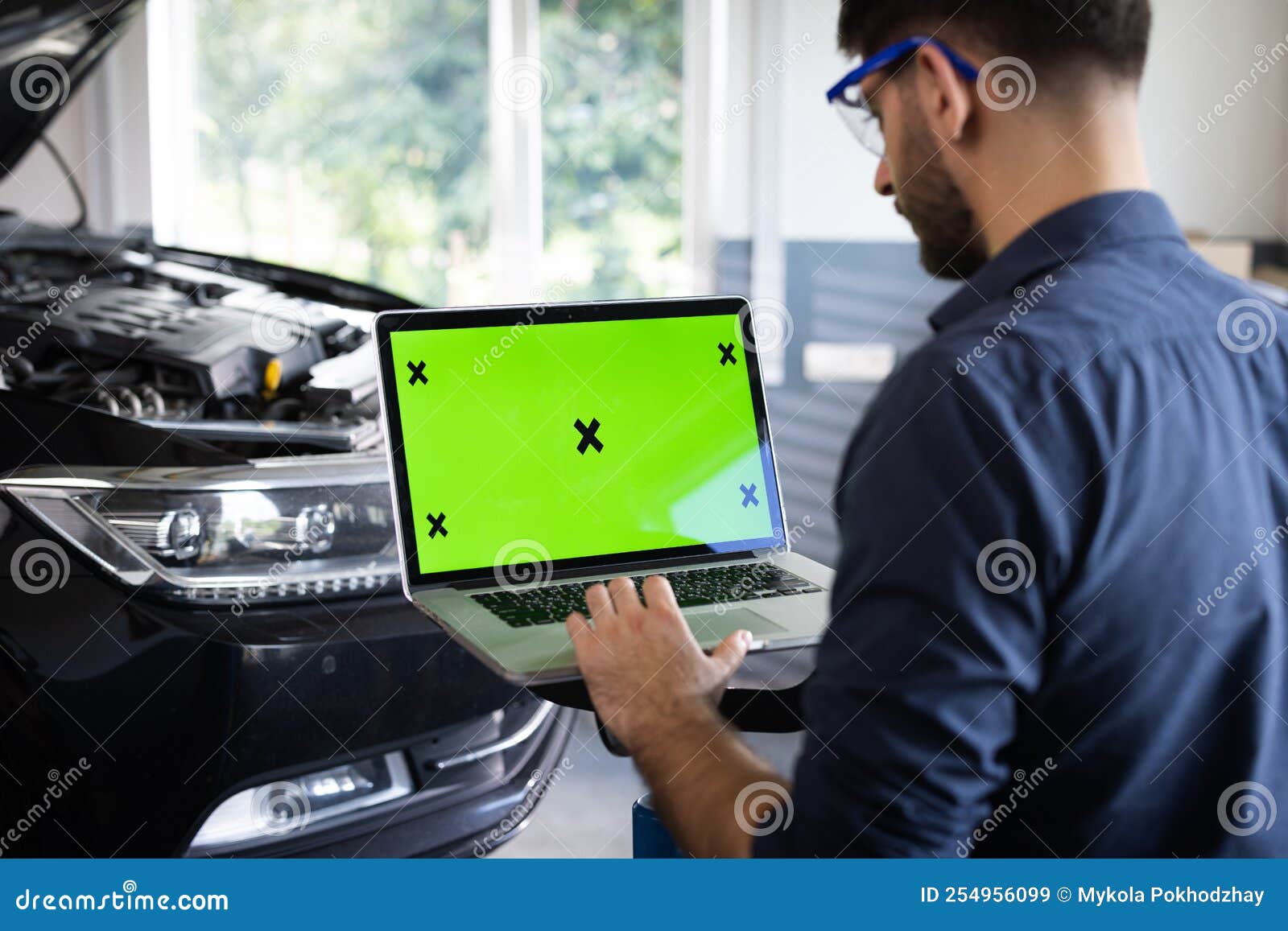 Car Service Mechanic is Running Diagnostics Software on an Advanced