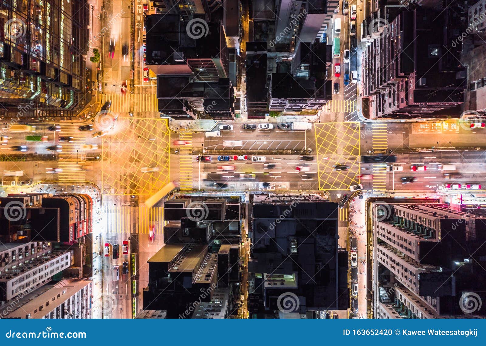 car, taxi, and bus traffic on road intersection at night in hong kong downtown district, drone aerial top view. asia city life