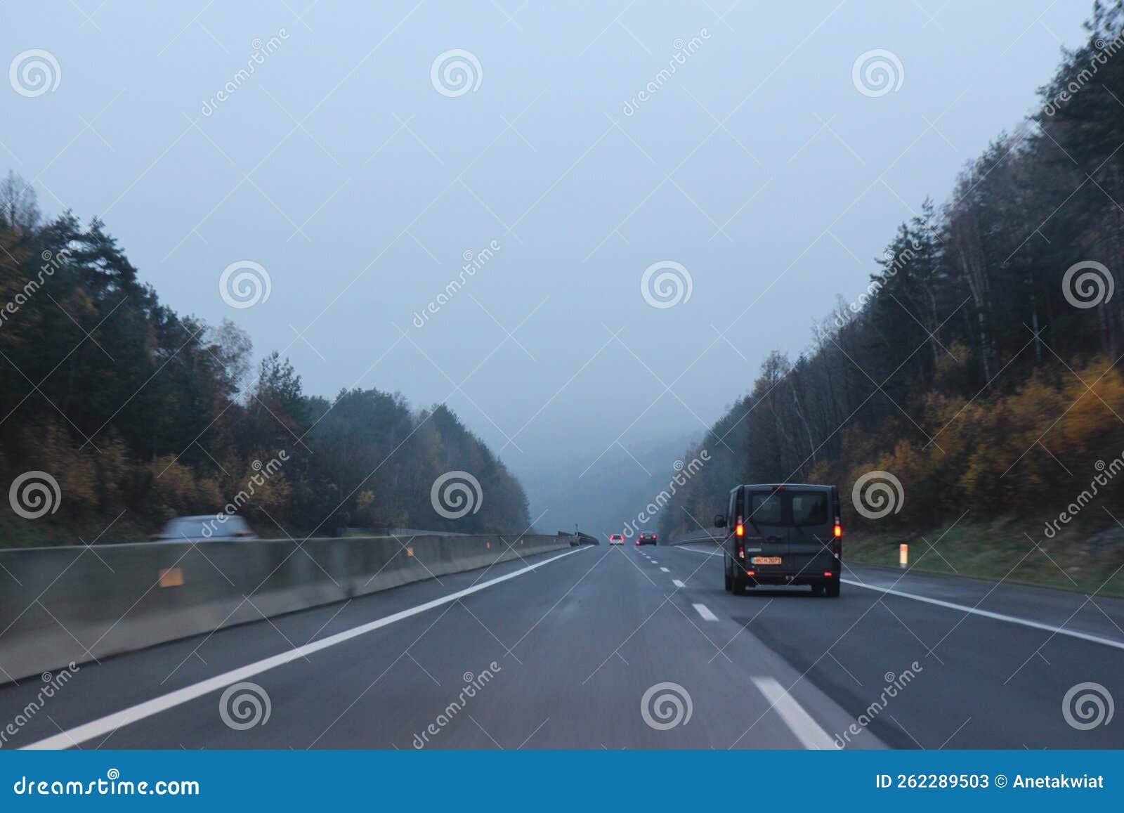 car traffic on higway with fog and autumn forest on sides