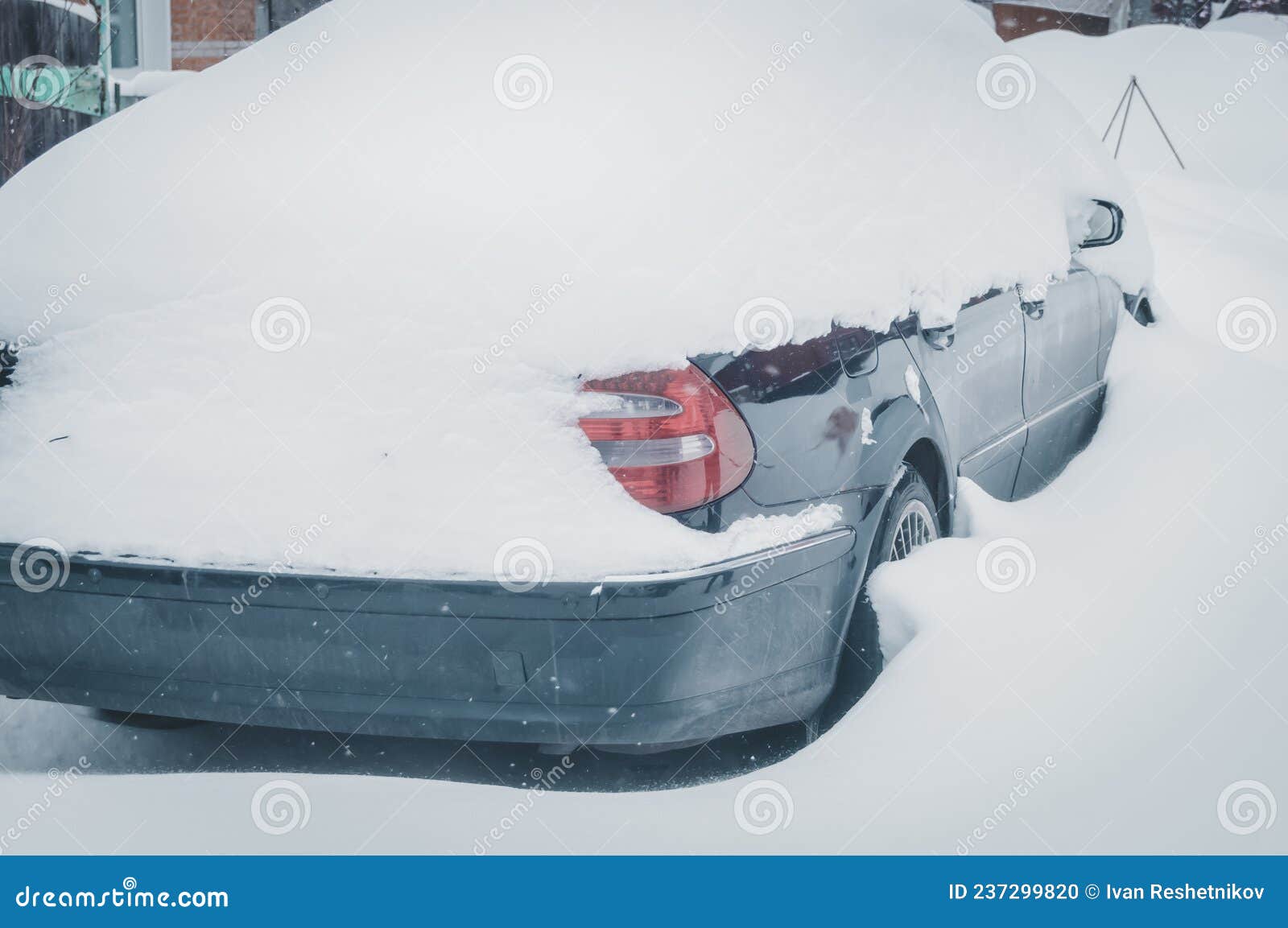 A Car Under a Snow Drift. Heavily Snowcovered Car in the Parking Lot
