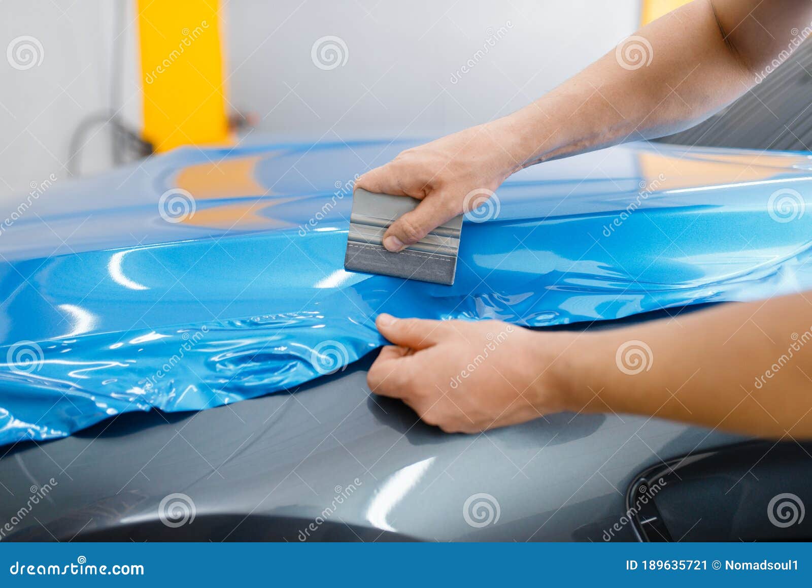 car wrapping, mechanic with squeegee installs film