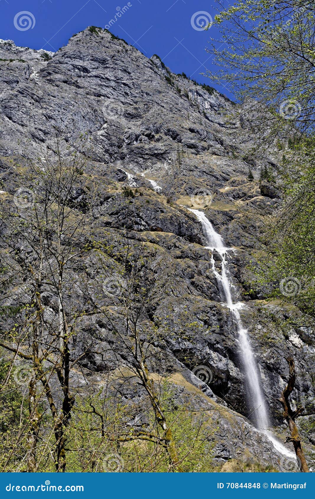 Cara de la roca con pequeño flujo de la avalancha en la primavera. Una cara escarpada de la roca donde una pequeña avalancha fluye abajo por un día soleado en la primavera (parque nacional de Berchtesgaden, montañas bávaras, Alemania)