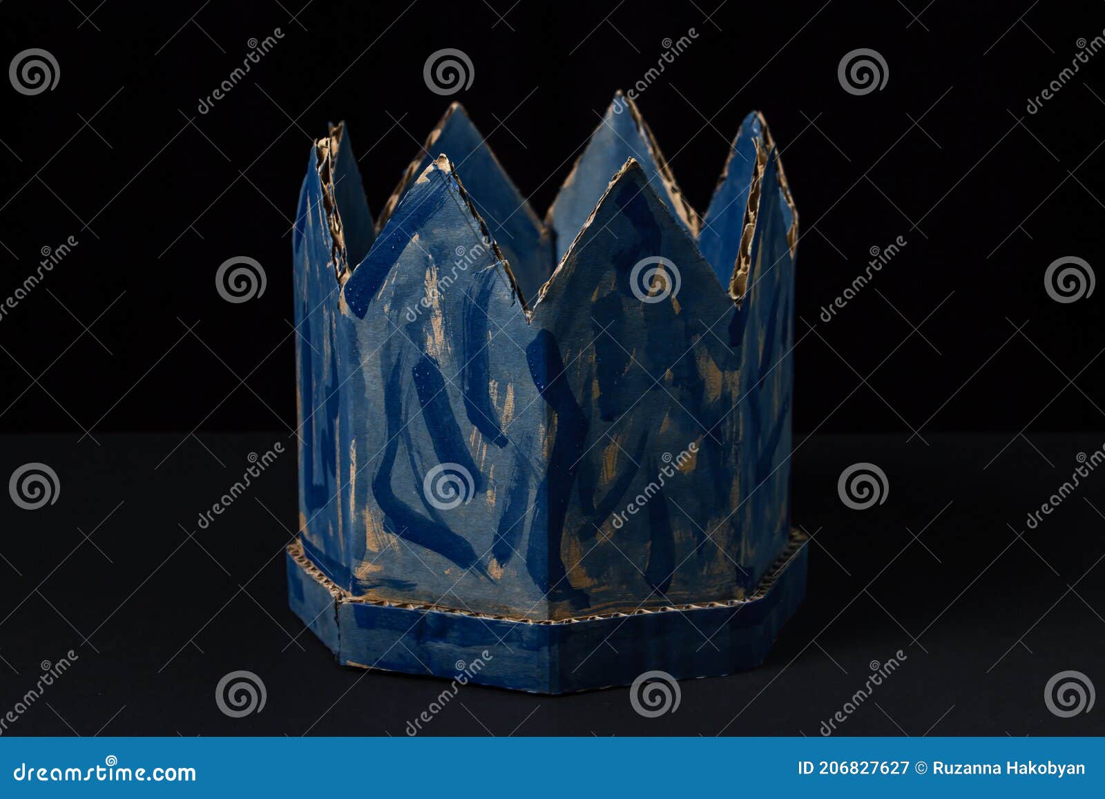 Cardboard crown on a black background. Paper product. Fake crown. A sloppy blue crown. Lie power