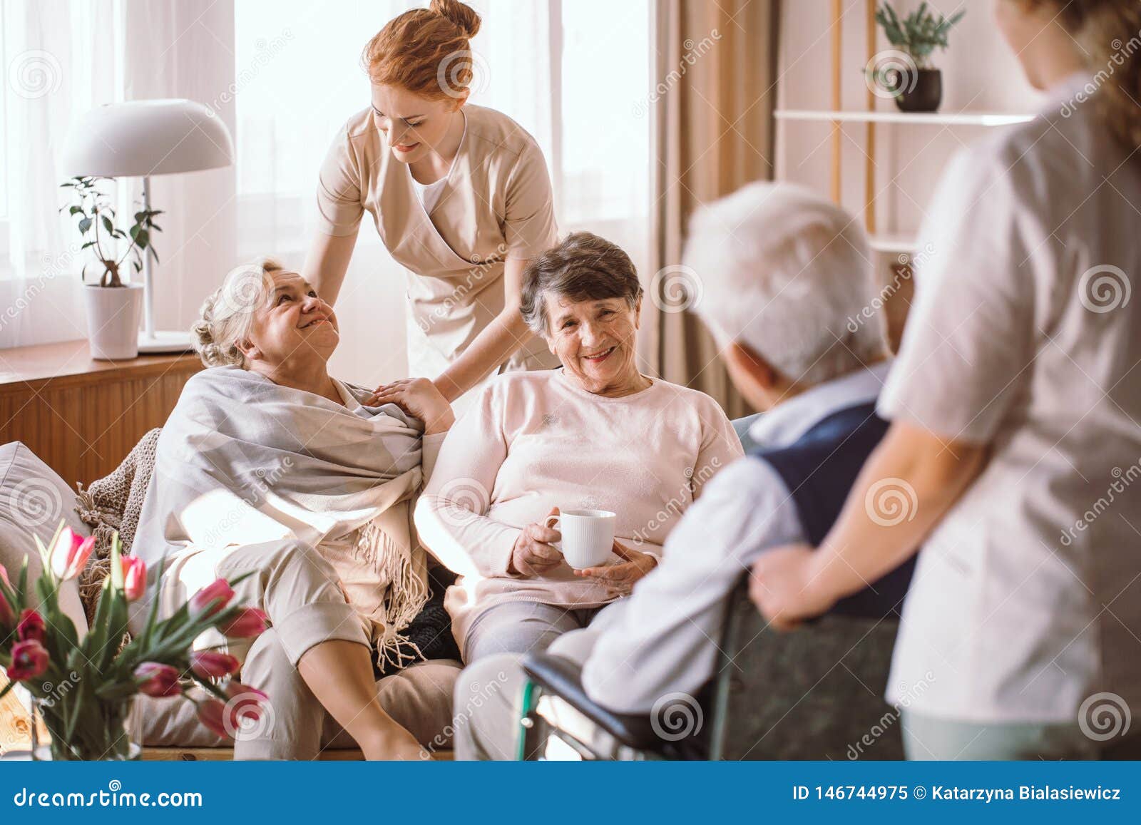 young caregiver comforting elderly woman in nursing home