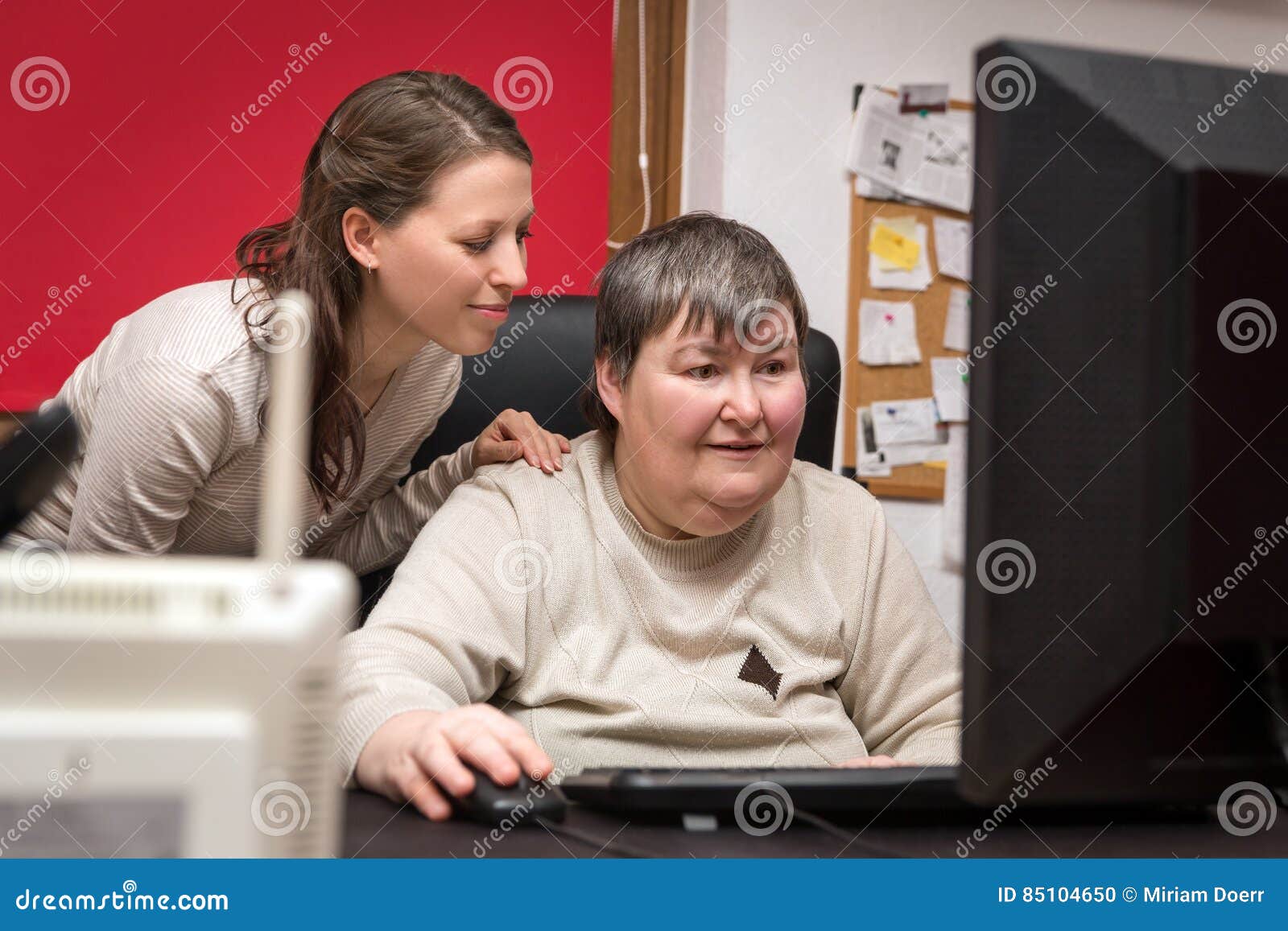 caregiver and mentally disabled woman learning at the computer