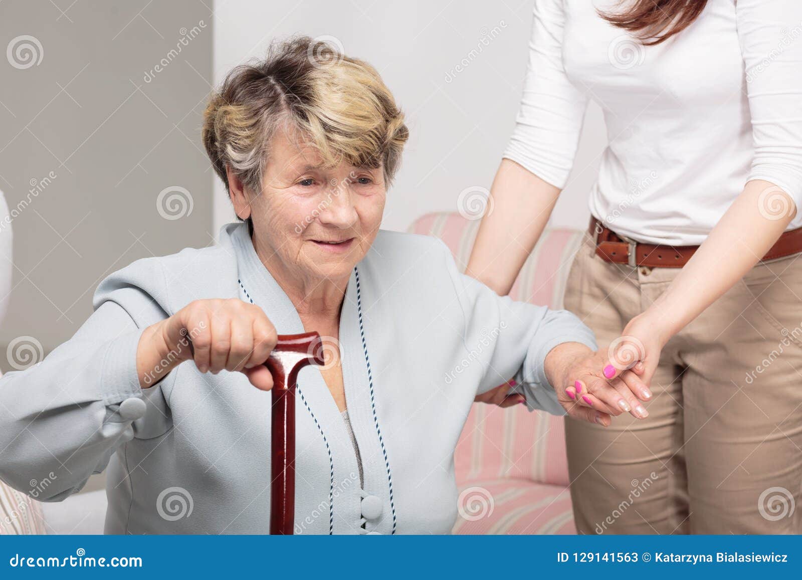 caregiver supporting senior woman with walking stick