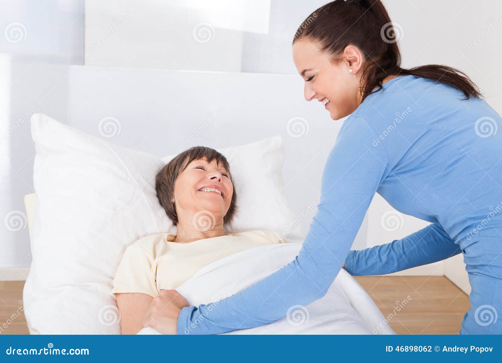 caretaker covering senior woman with blanket