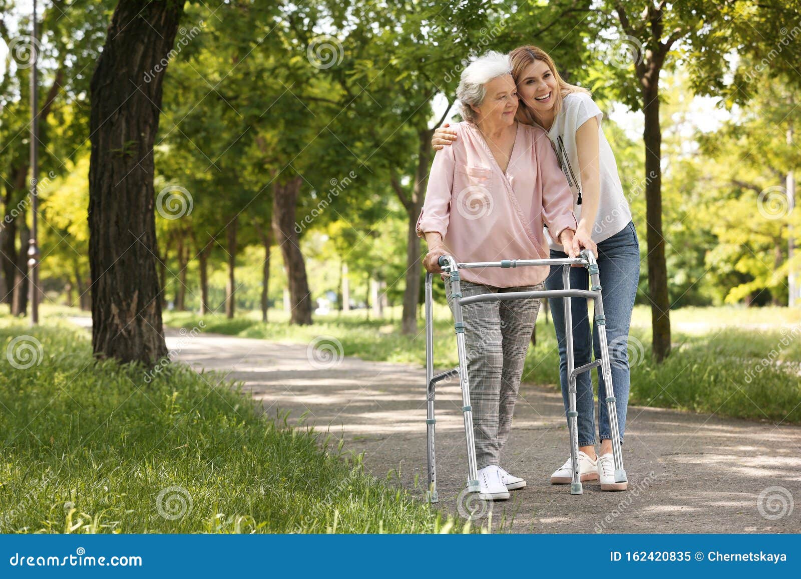 caretaker helping elderly woman with walking frame
