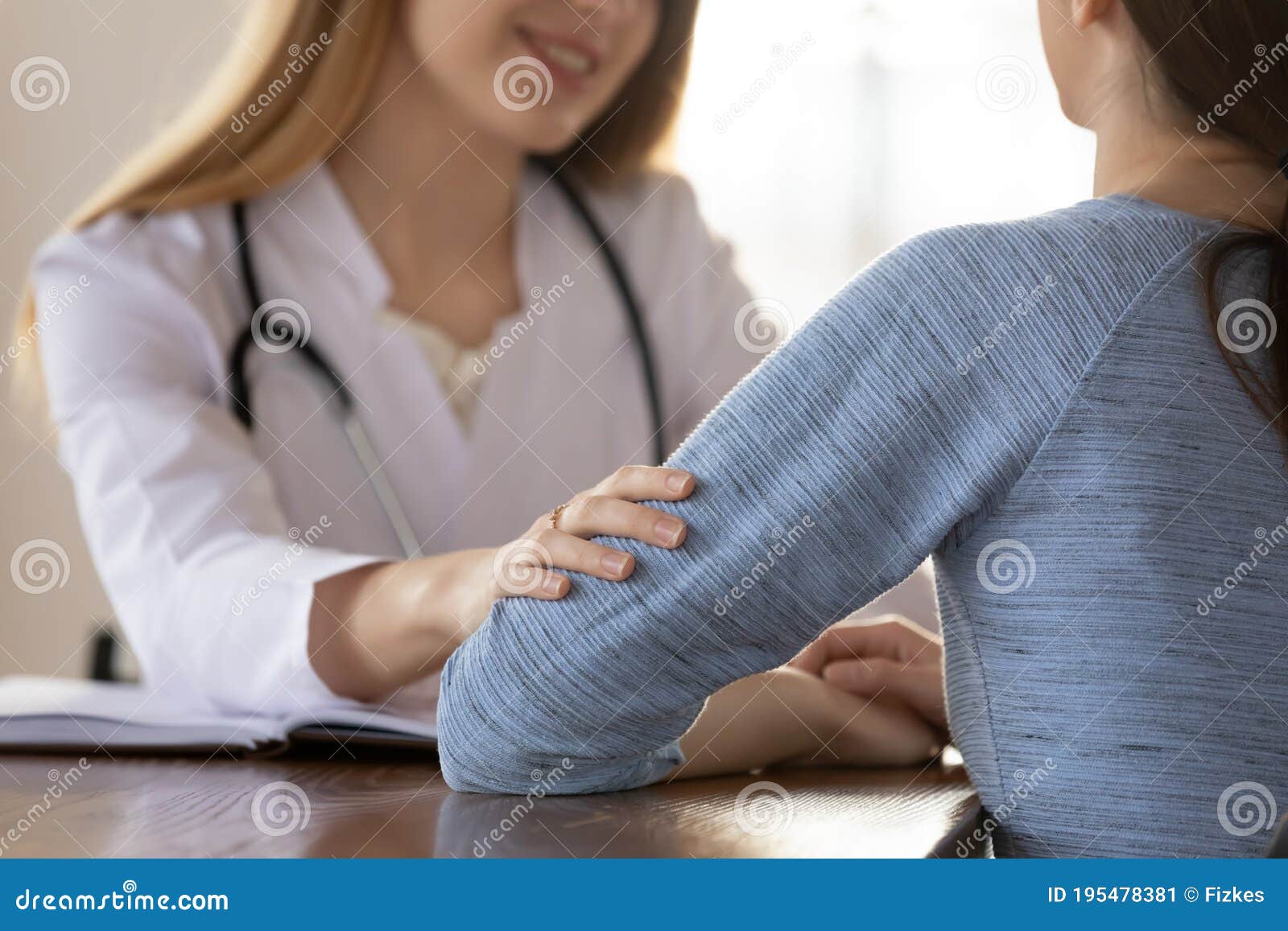 caring female doctor comforting young woman patient at meeting