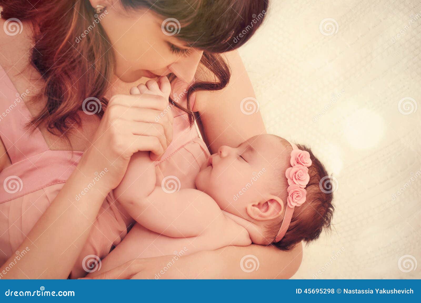 caring mother kissing little fingers of her cute sleeping baby g