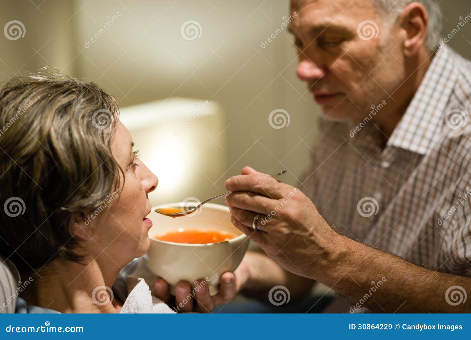 caring senior man feeding his sick wife