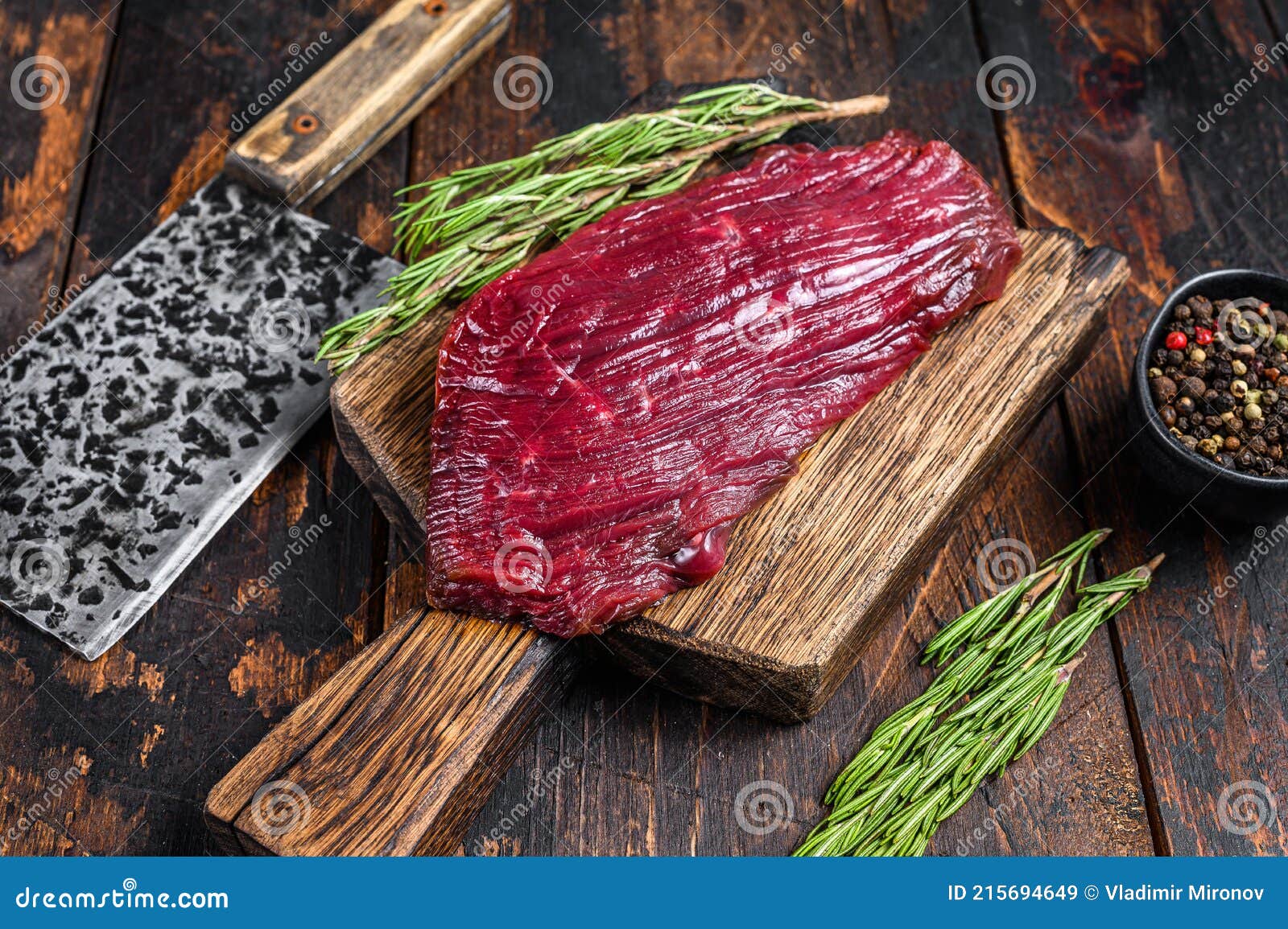 Carne Cruda De Venado En Una Tabla De Cortar Con Romero. Fondo Negro