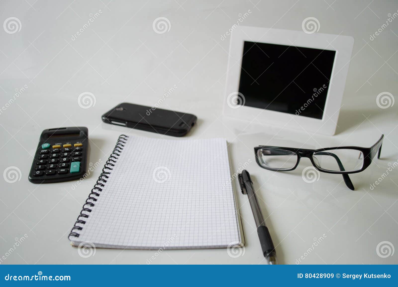 Carnet, stylo, verres et cadre sur un fond blanc