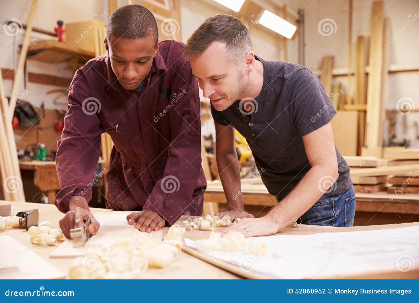 Carpenter With Apprentice Planing Wood In Workshop Stock ...