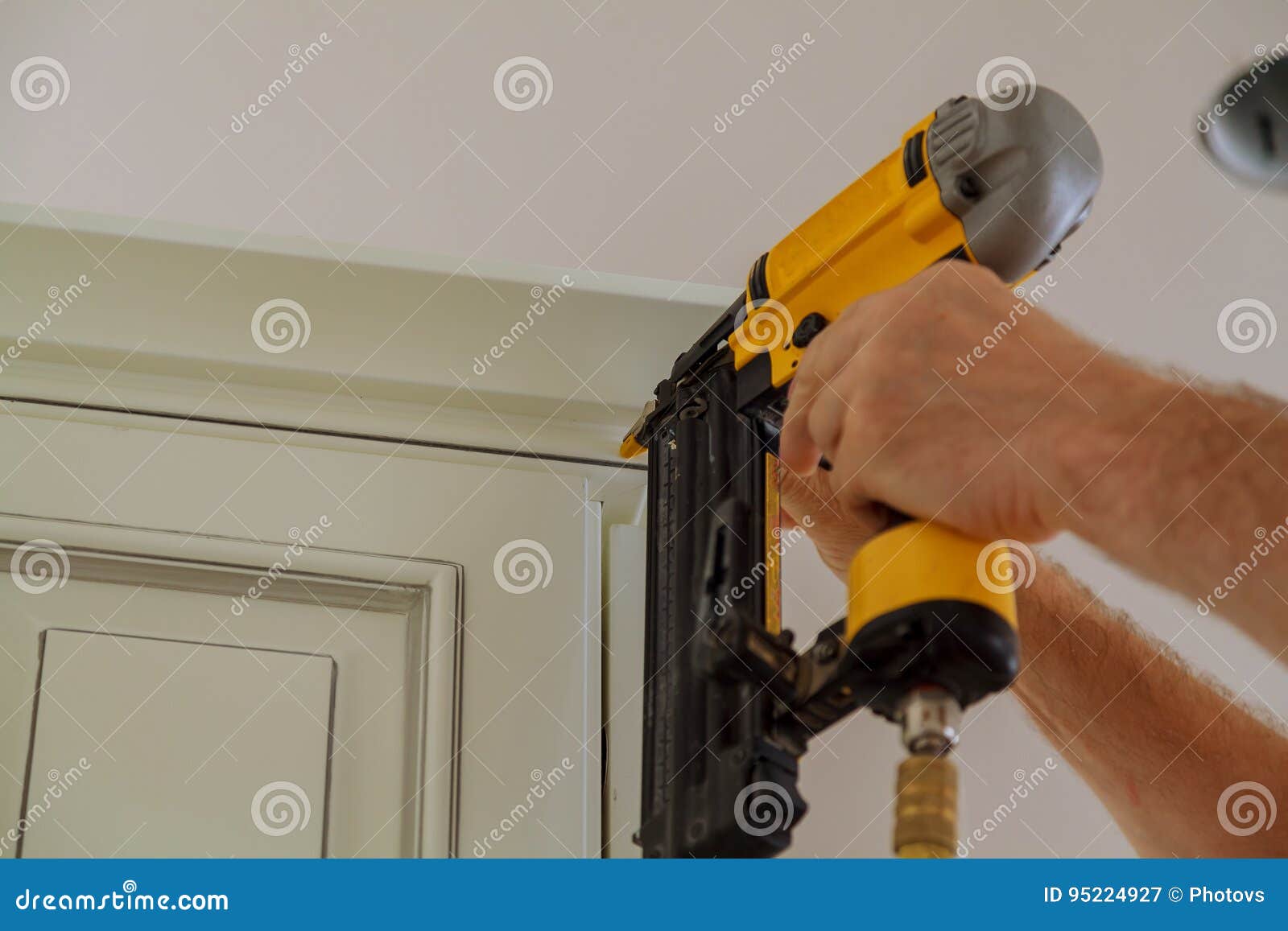 carpenter brad using nail gun to crown moulding on kitchen cabinets framing trim,