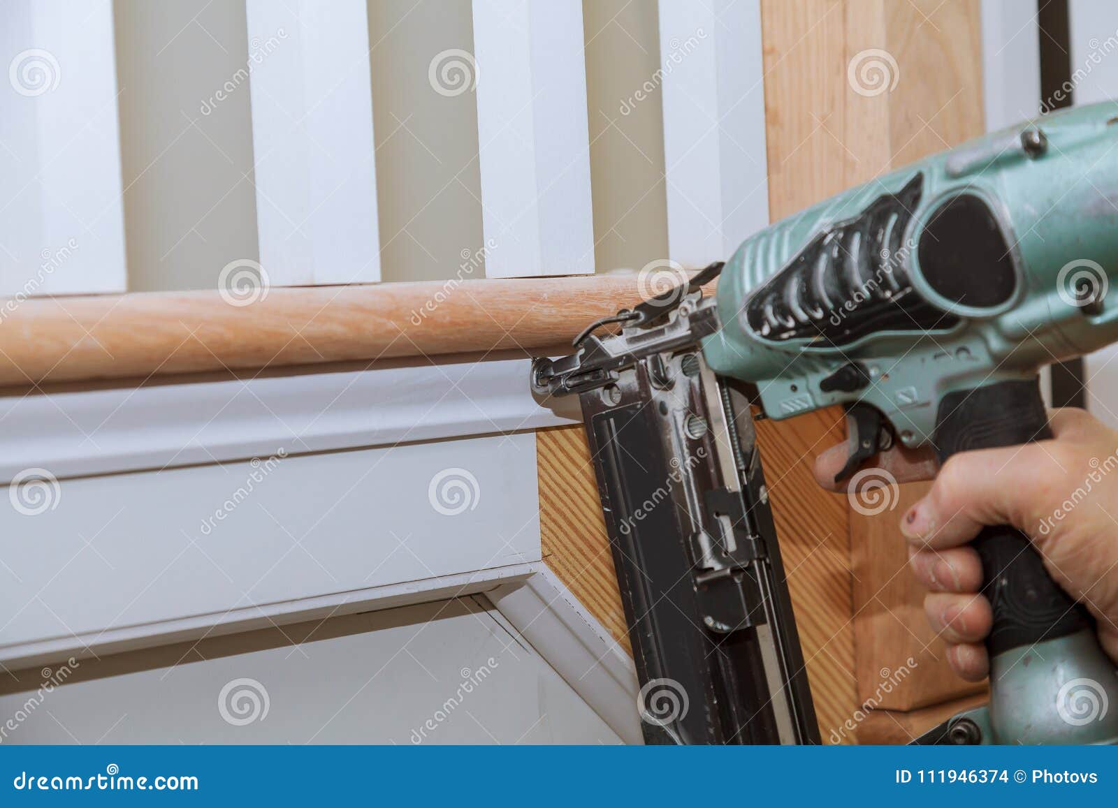 carpenter brad using nail gun to moulding trim, with the warning label that all power tools