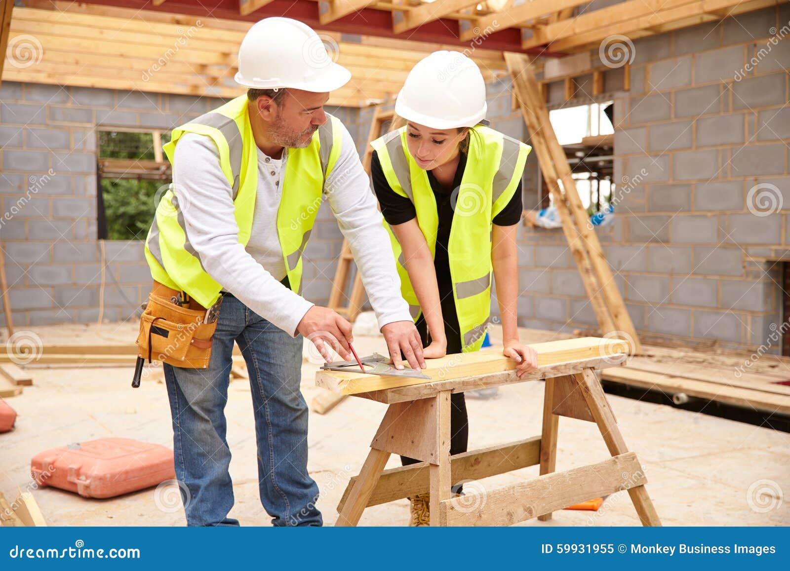carpenter with female apprentice working on building site