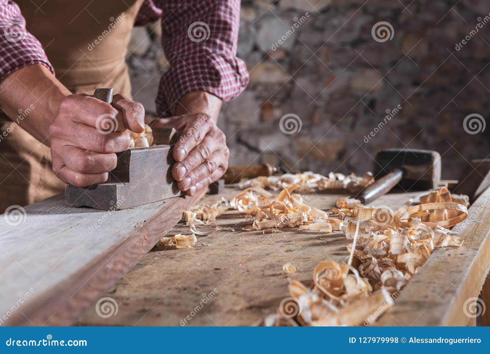 carpenter smoothing out long wooden beam with tool