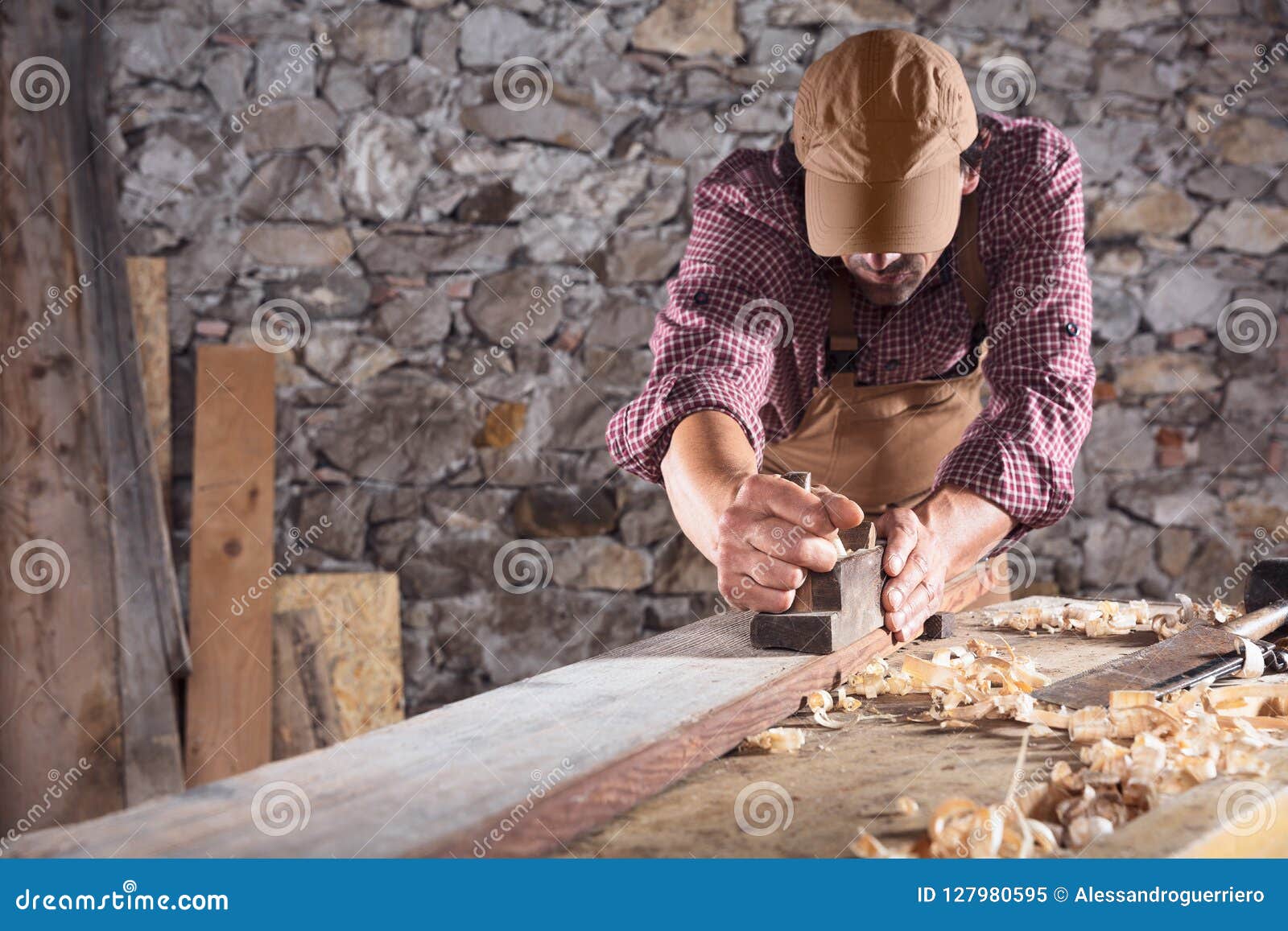 carpenter smoothing out long wooden beam with tool