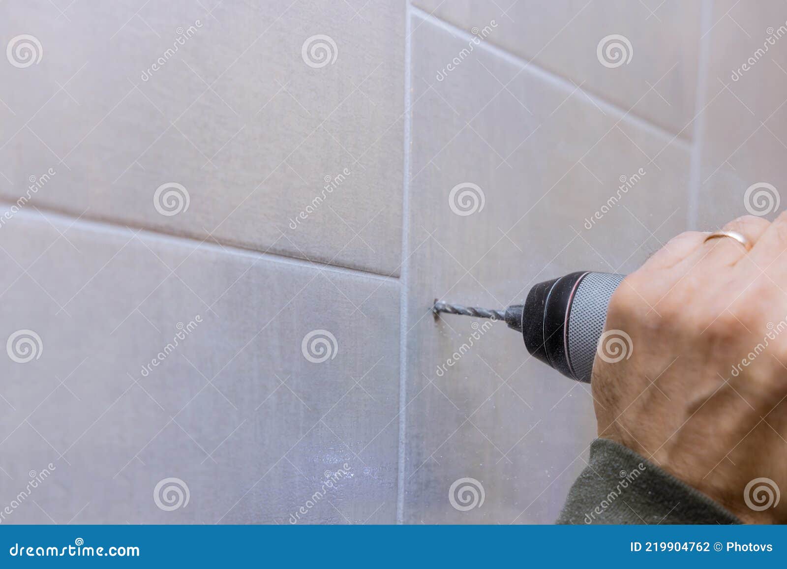 Carpenter in Work on Drilling Hole in Bathroom Wall for Installing