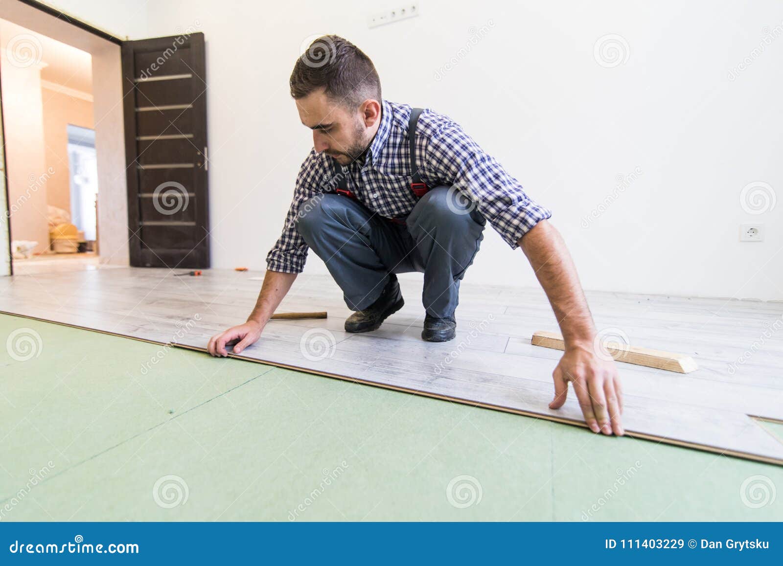 Carpenter Worker Man Installing Wood Parquet Board During Flooring