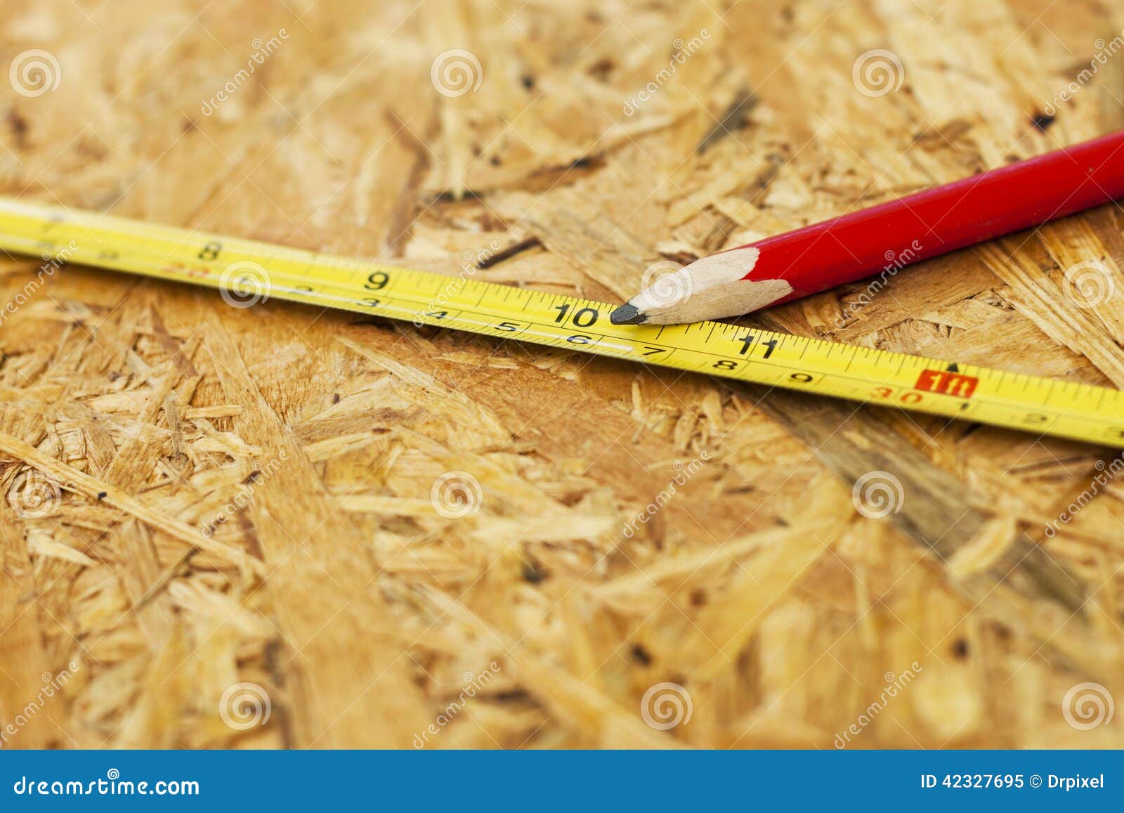 Carpentry concept. Close up pencil and measure tape on wooden board