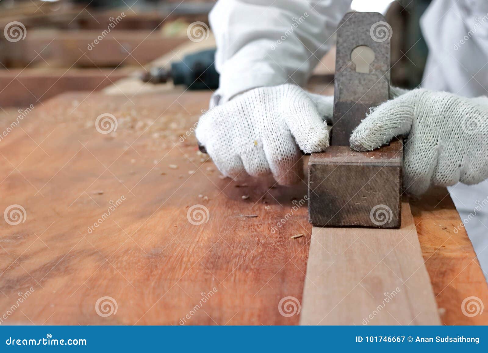 Carpintero que acepilla un tablón de la madera usando una alisadora de la mano en taller de la carpintería