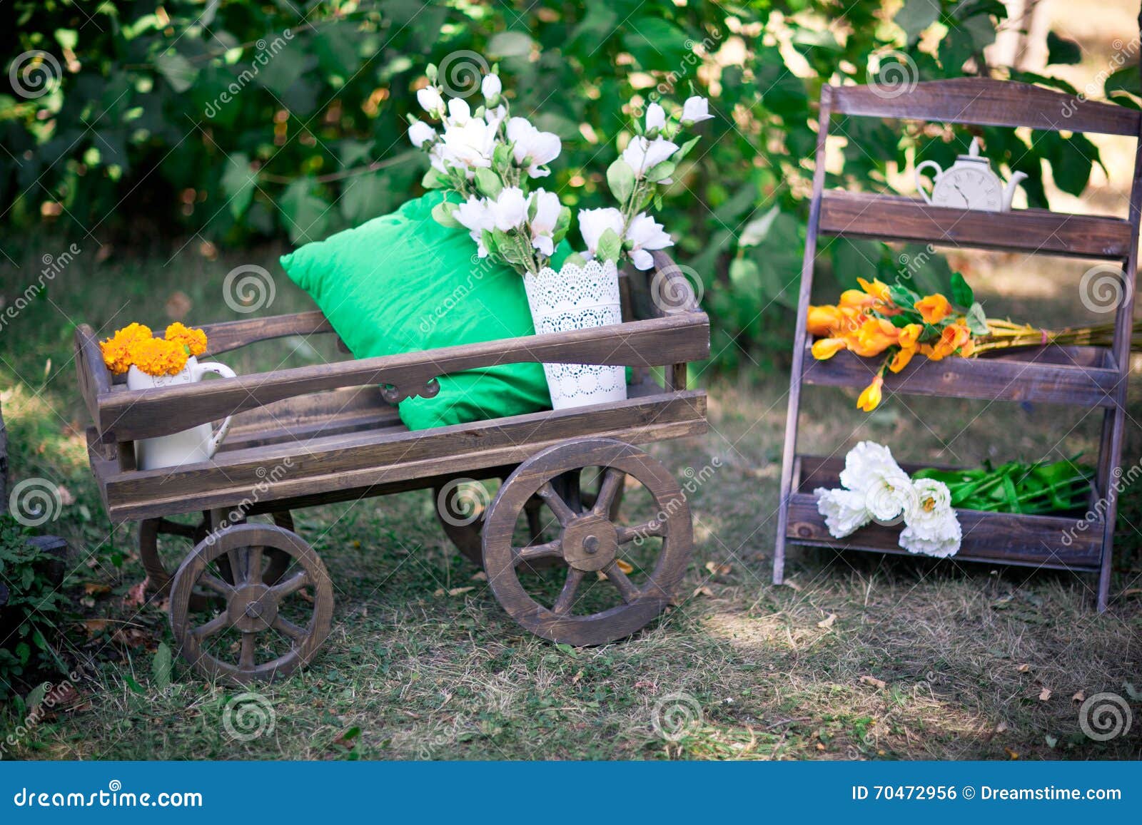 Carrello di legno, supporto di legno decorativo, vaso del metallo bianco, prato verde, cuscino verde