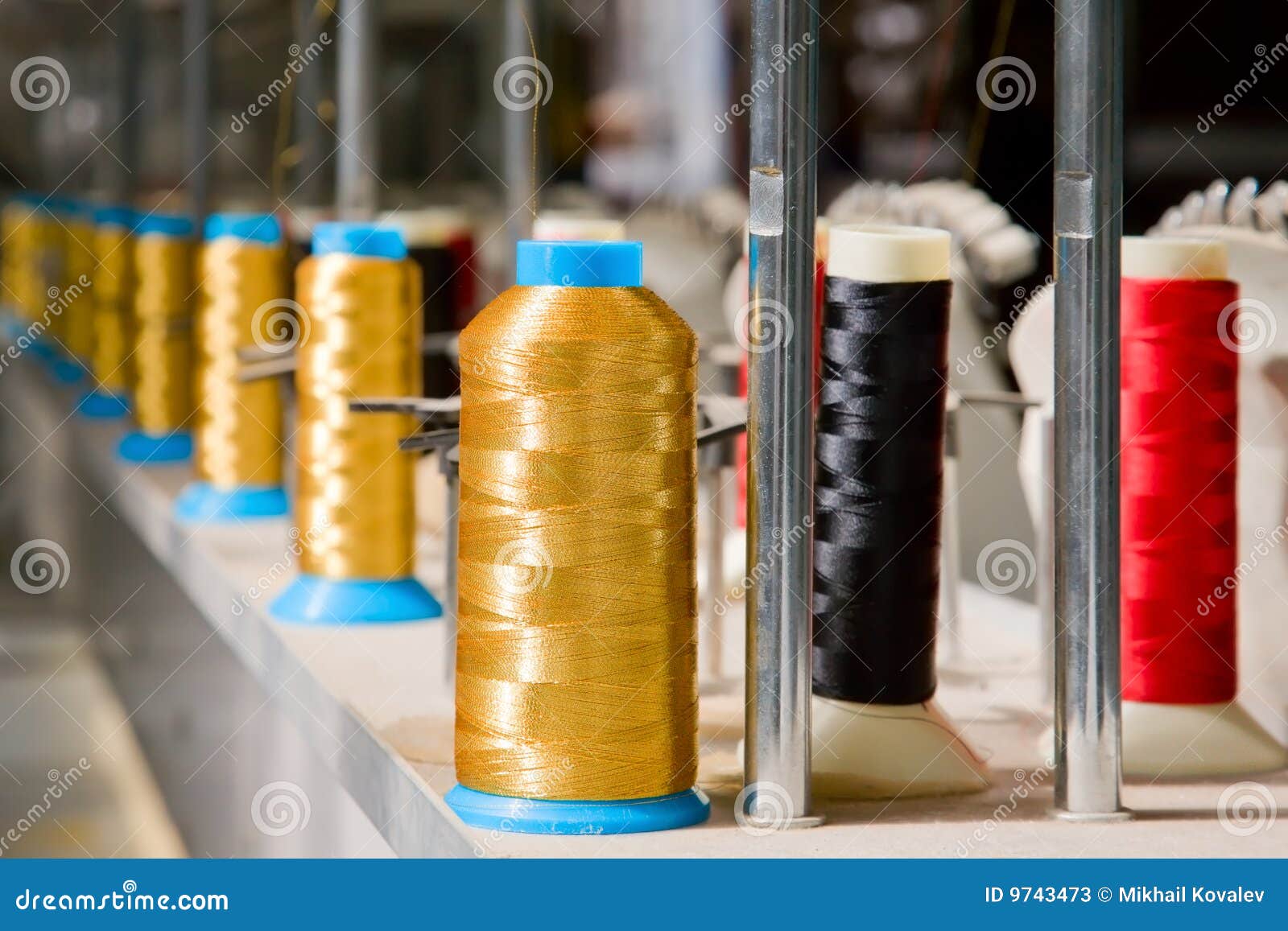 Fila larga de los carretes coloreados de la tela en la fabricación