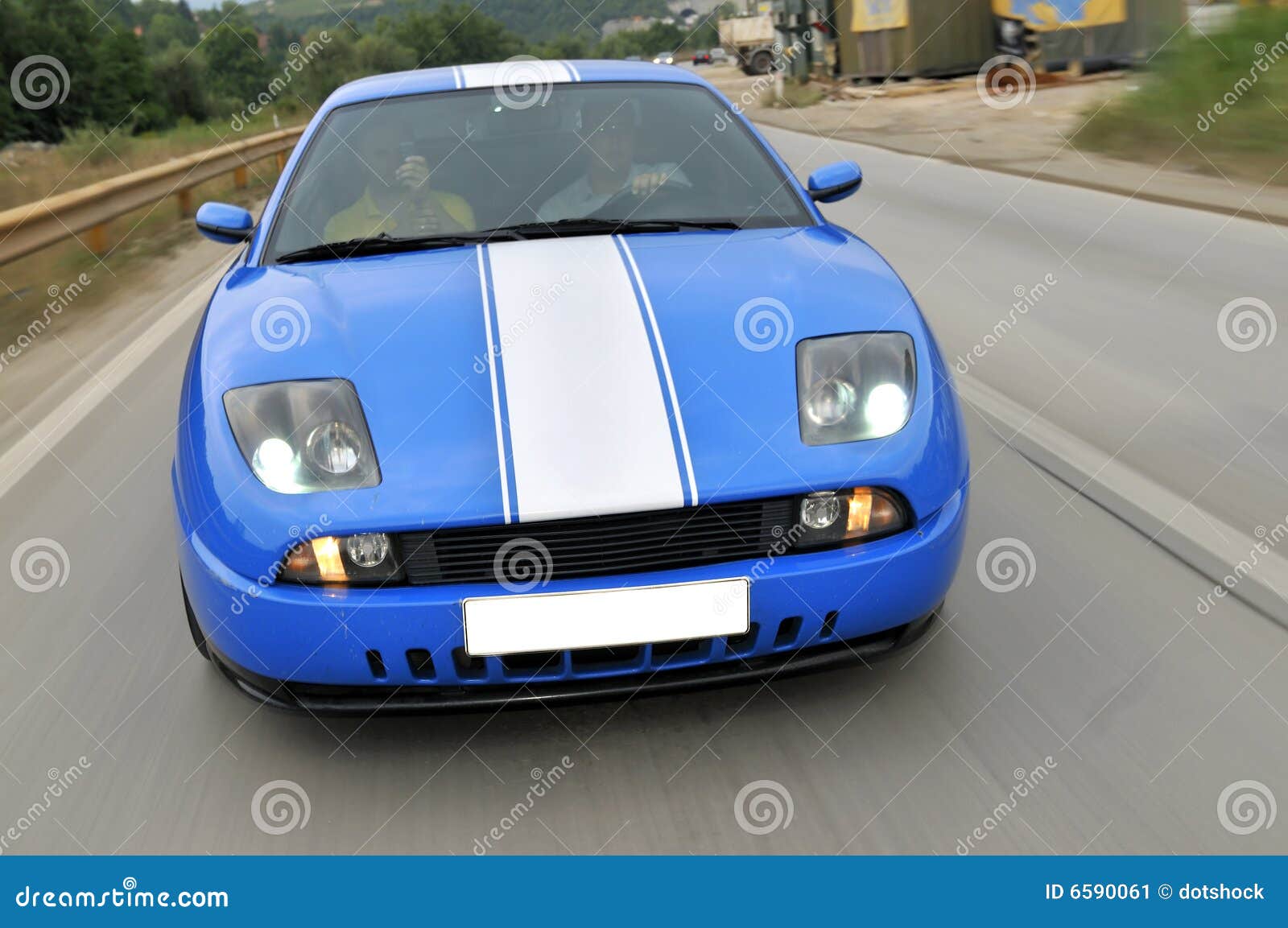 Carro desportivo rápido azul na estrada. A movimentação azul do carro de competência do esporte rapidamente na estrada capturou com exposição longa