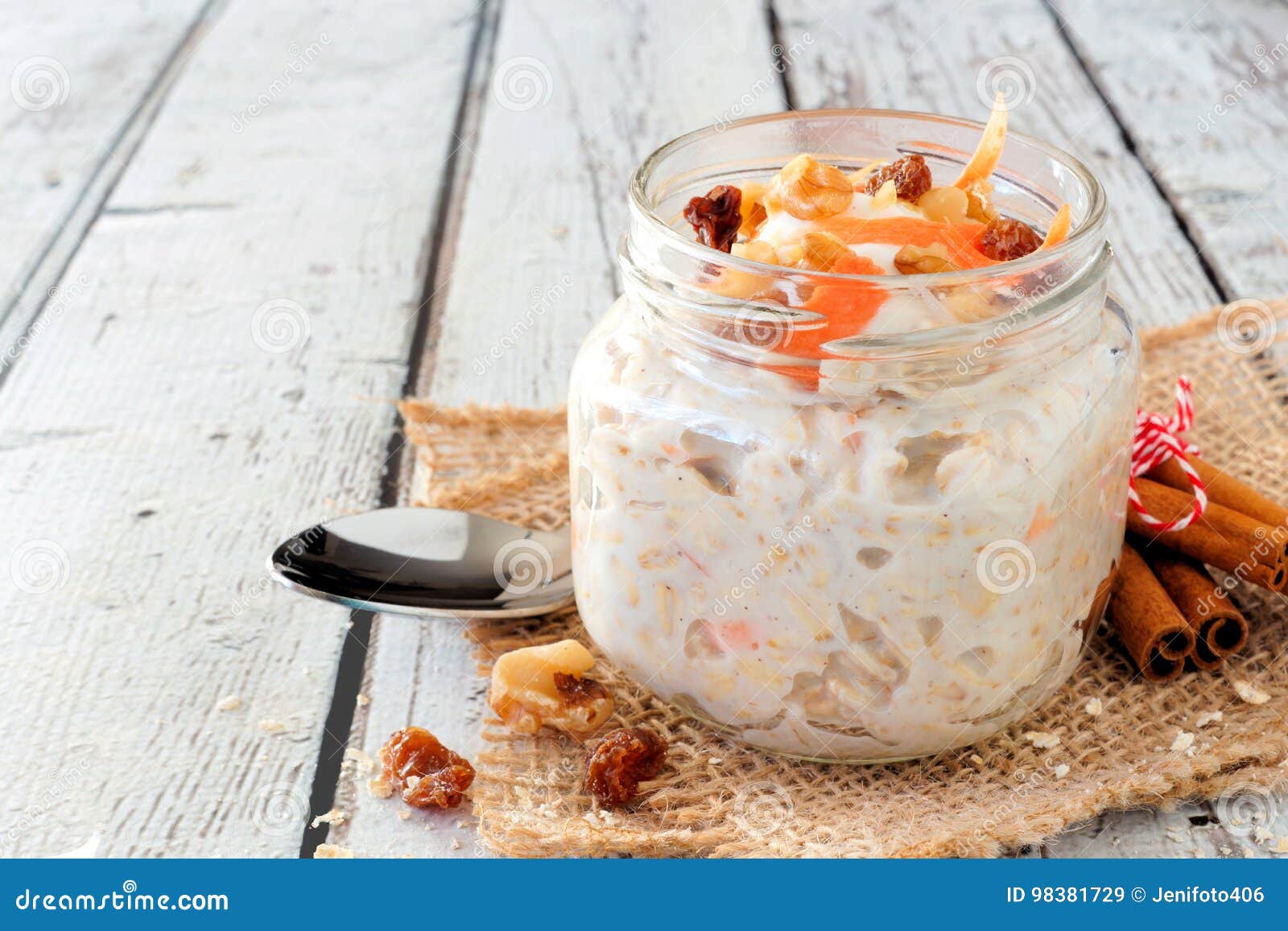 carrot overnight oats with nuts and raisins in a mason jar on white wood