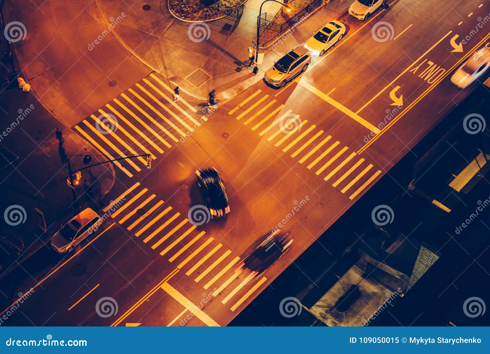 cars and people on road intersection with signal lights and crosswalks at night time in the city street.