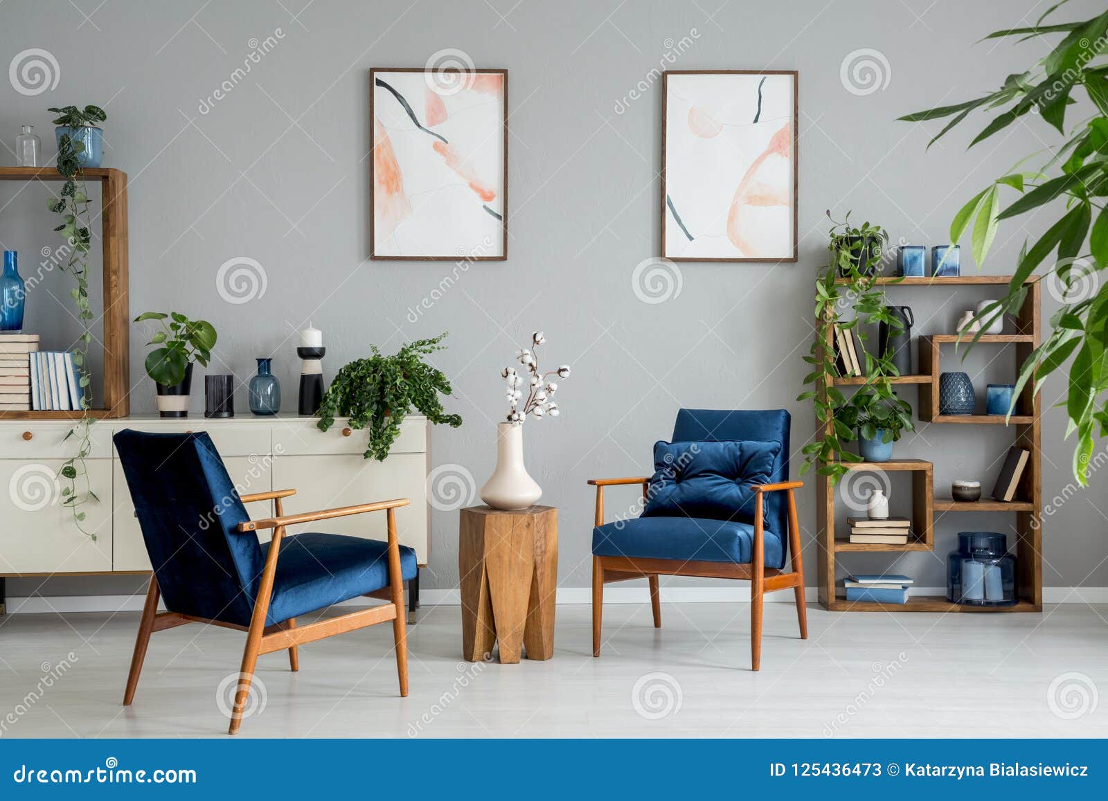 Cartazes e plantas no interior brilhante da sala de visitas com poltronas e flores dos azuis marinhos Conceito real da foto