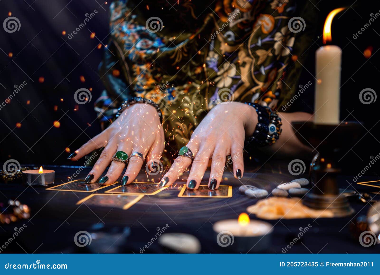 cartomancy. a fortune teller reads tarot cards. on the table are candles and fortune-telling objects and sparks. hands close up.