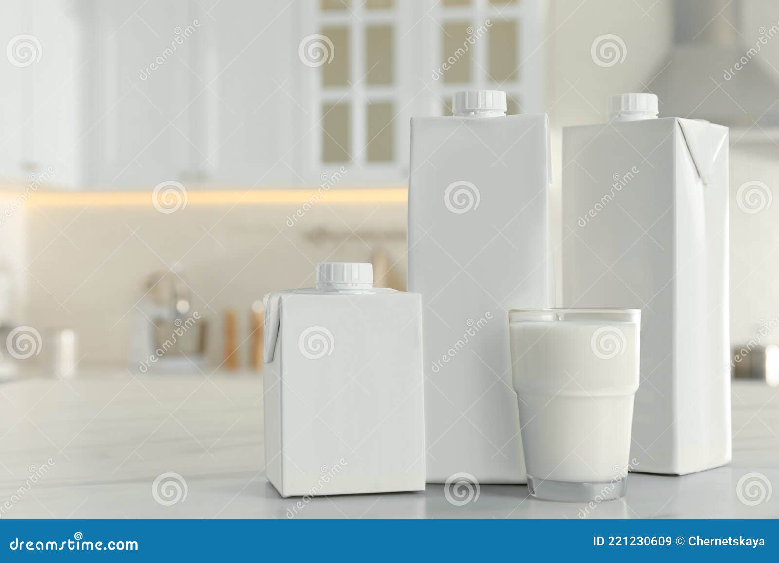 carton boxes and glass of milk on table in kitchen, space for text