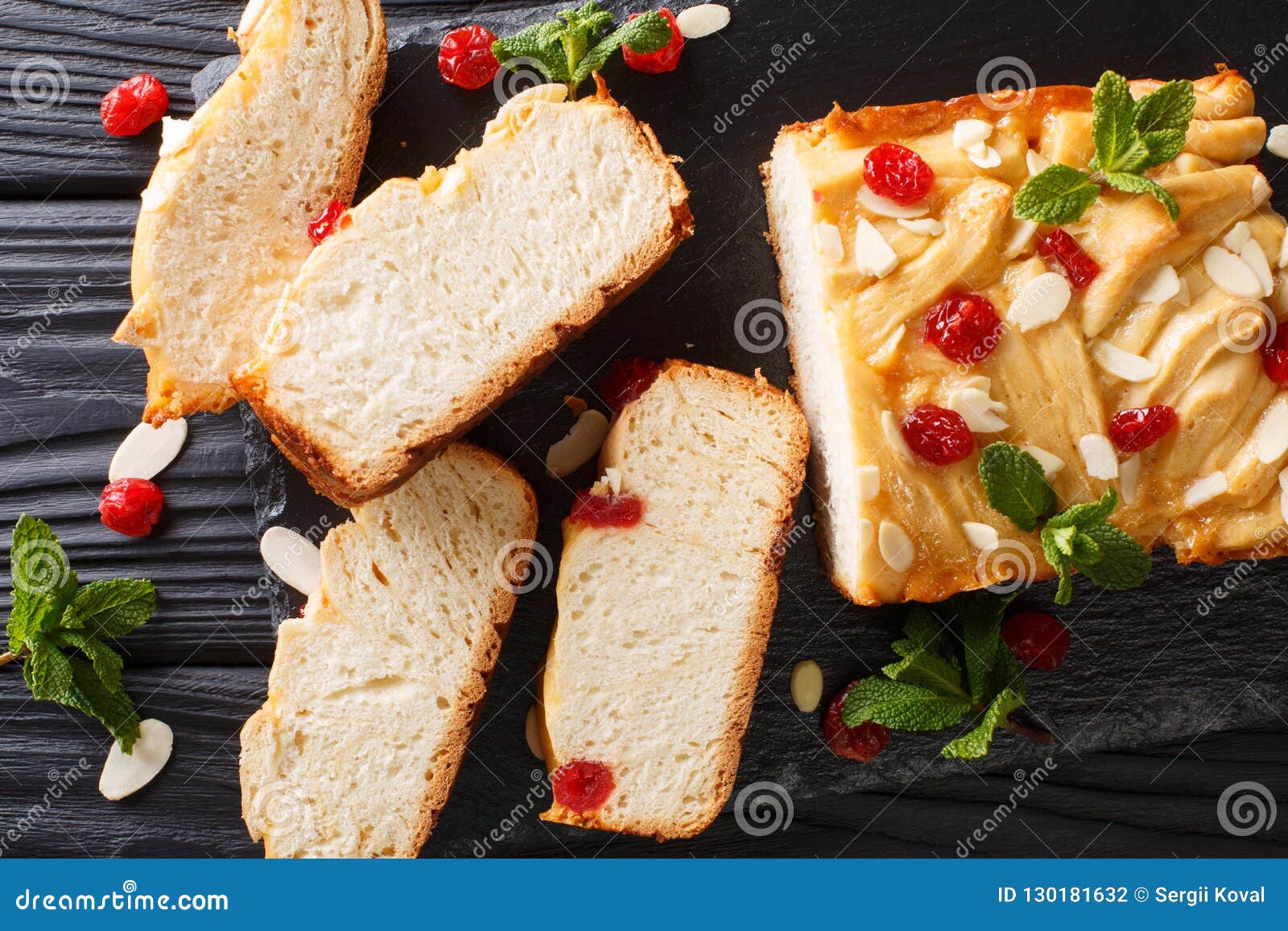 Caseiro cortou o pão de leite condensado com cerejas secadas, amêndoa. Pão de leite condensado cortado caseiro com cerejas, as amêndoas e close-up secados da hortelã na tabela Vista superior horizontal de cima de