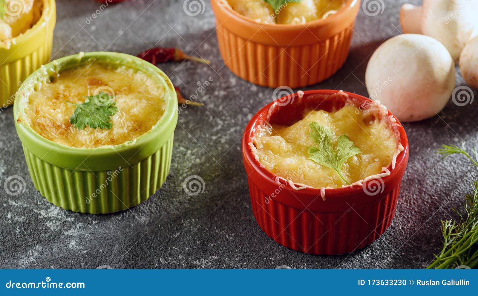 casserole with chicken and mushrooms under cheese crust in multicolored cocoanuts on gray background