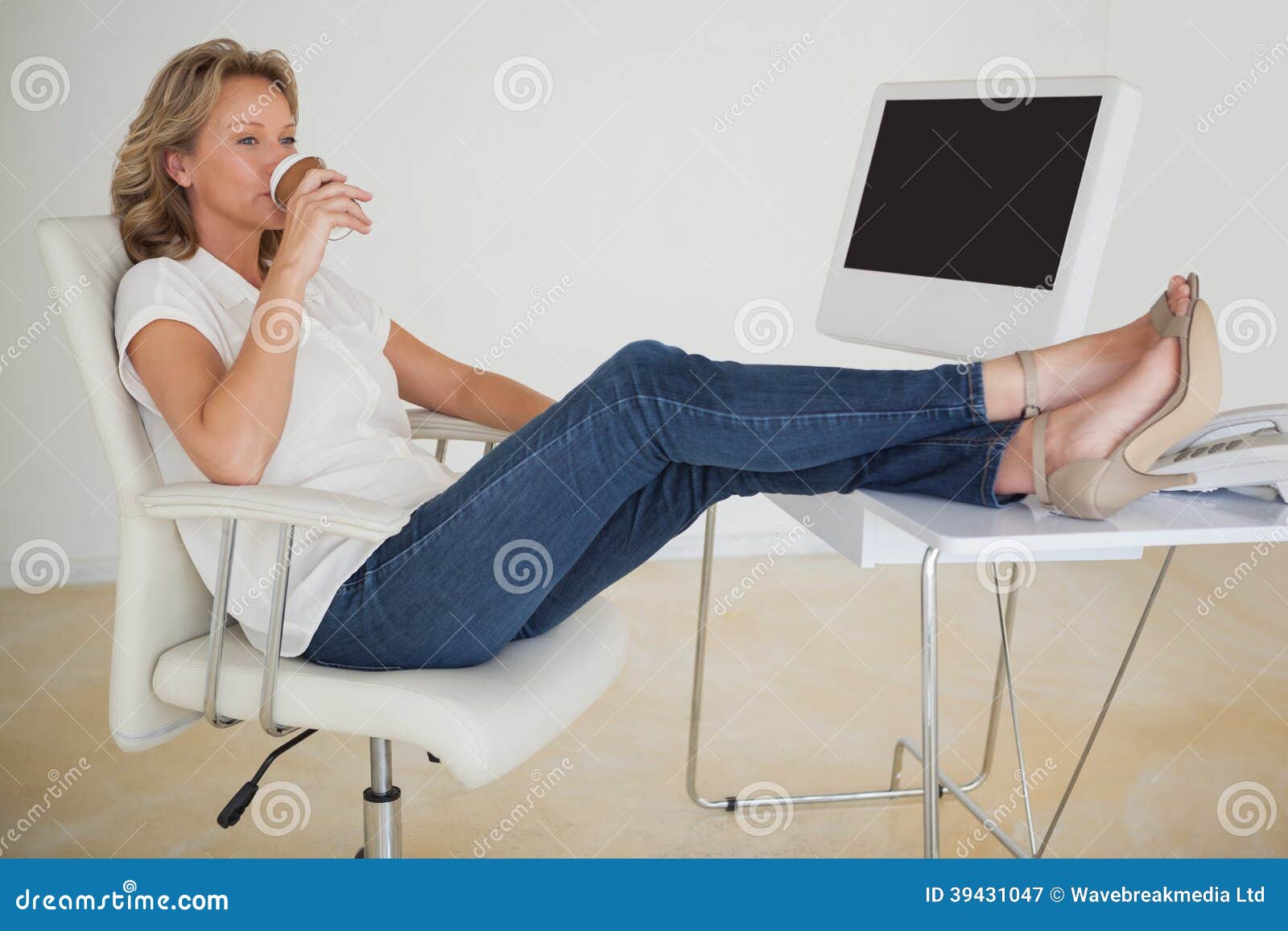 Casual Businesswoman Having A Coffee With Her Feet Up At Desk Stock