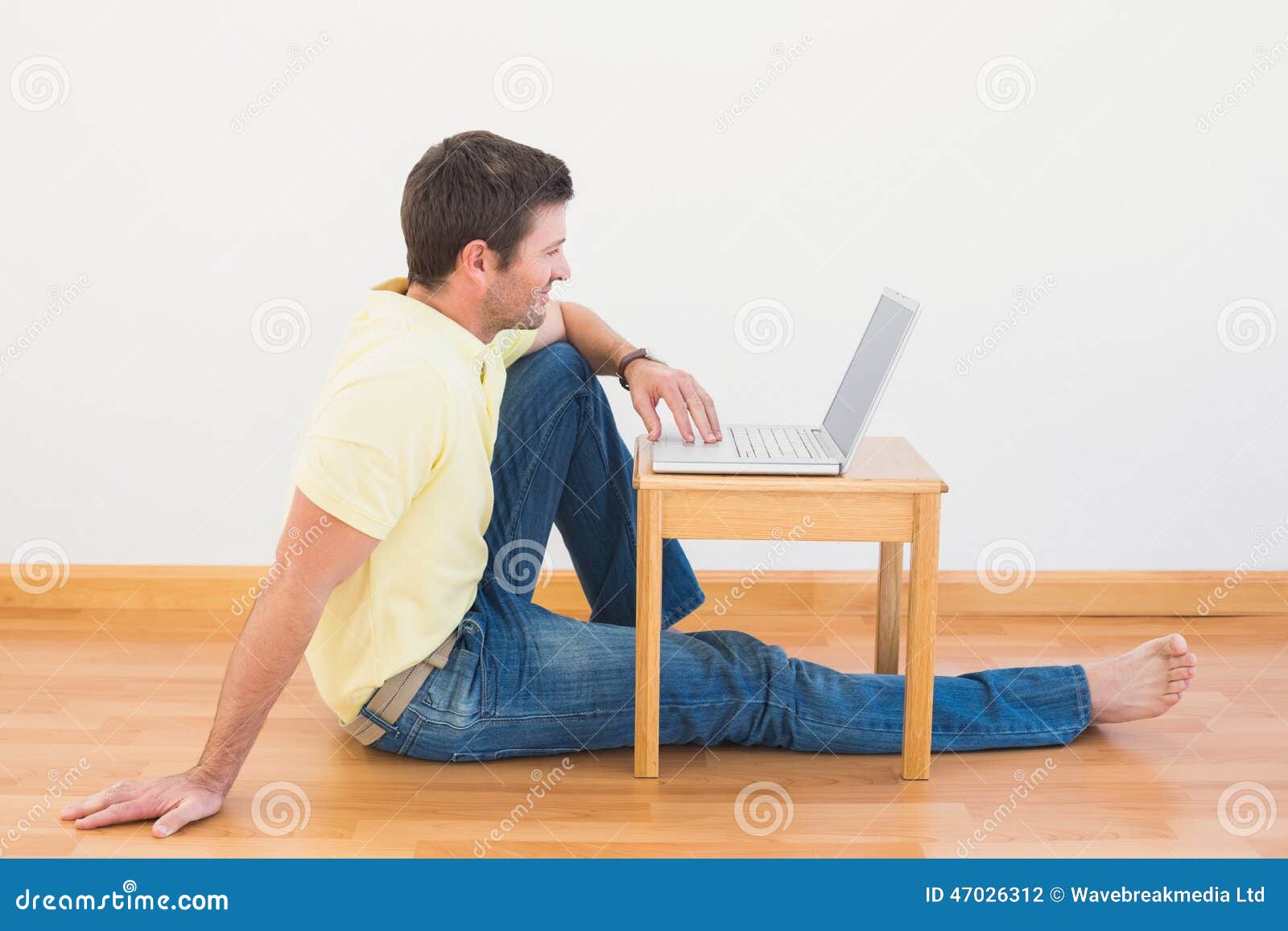 Casual Man Sitting On Floor Using Laptop On The Coffee 